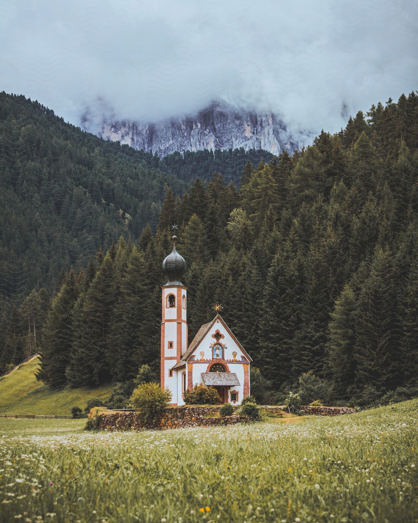 Church of st john surrounded by tall mountains and forest in the dolomites