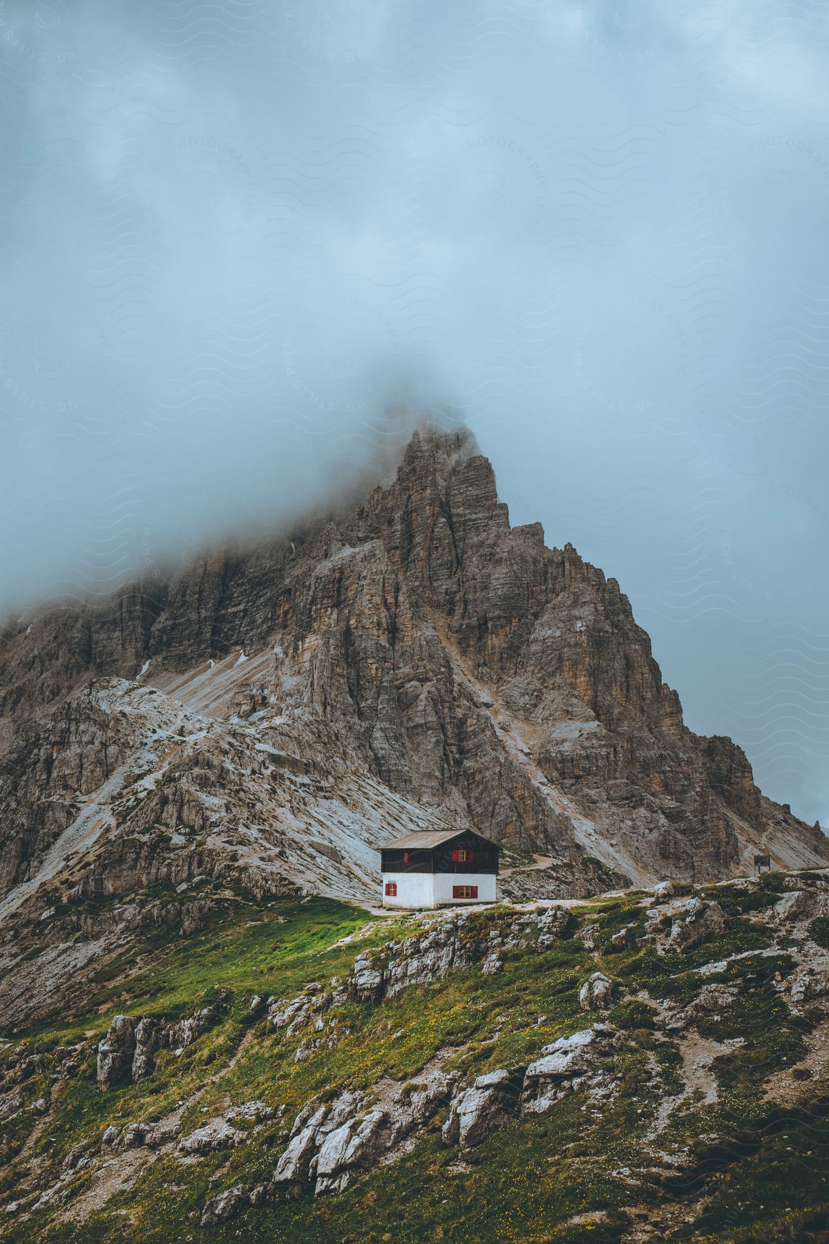 A black and white house next to a mountain with a peak in the clouds