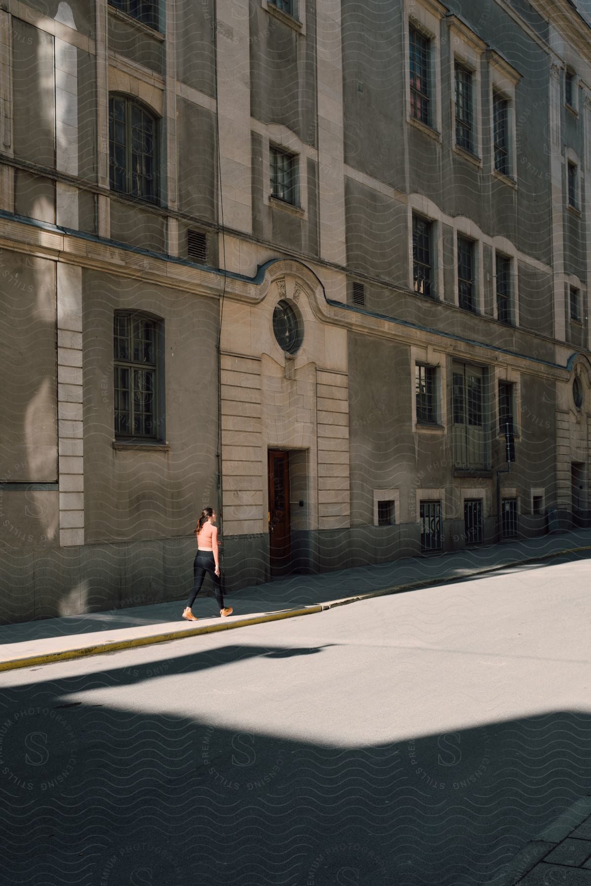 A young woman walking past a downtown city building on a sunny day