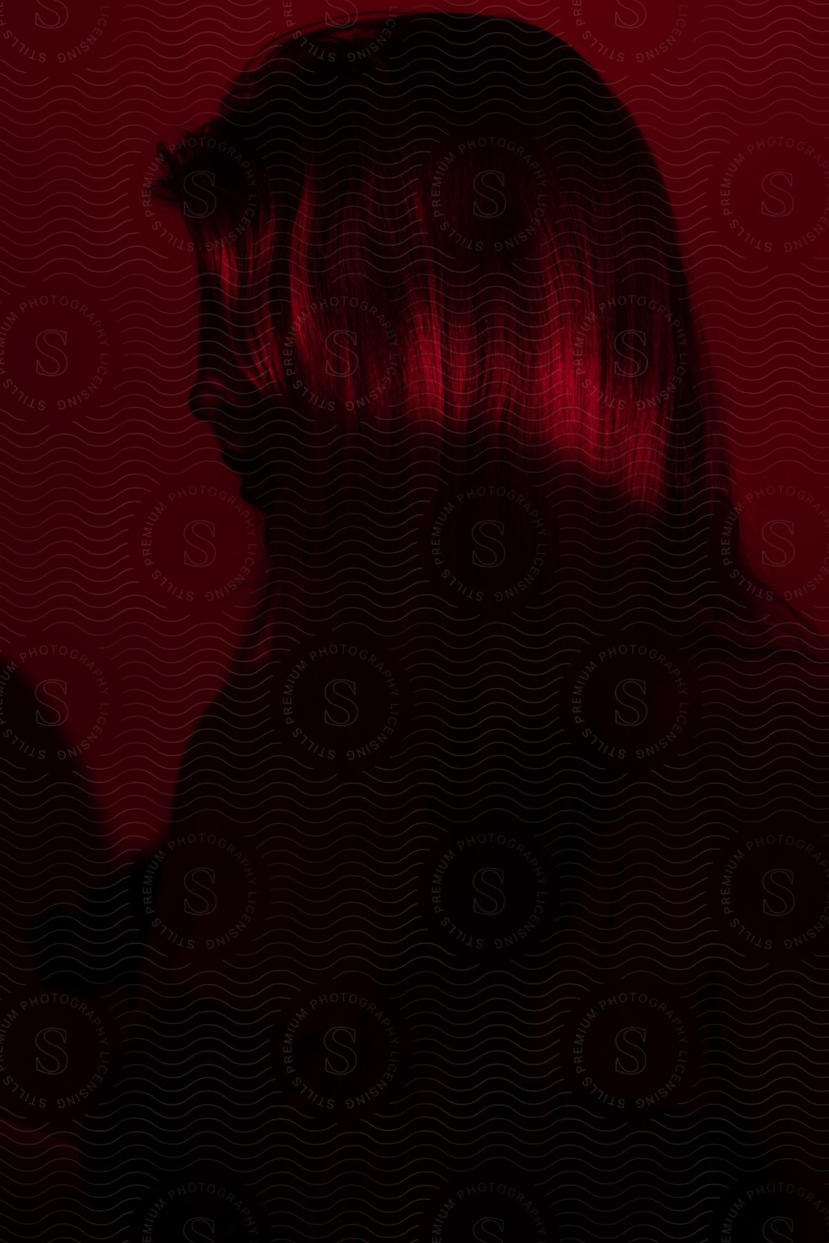 A woman poses from a side angle in a red room