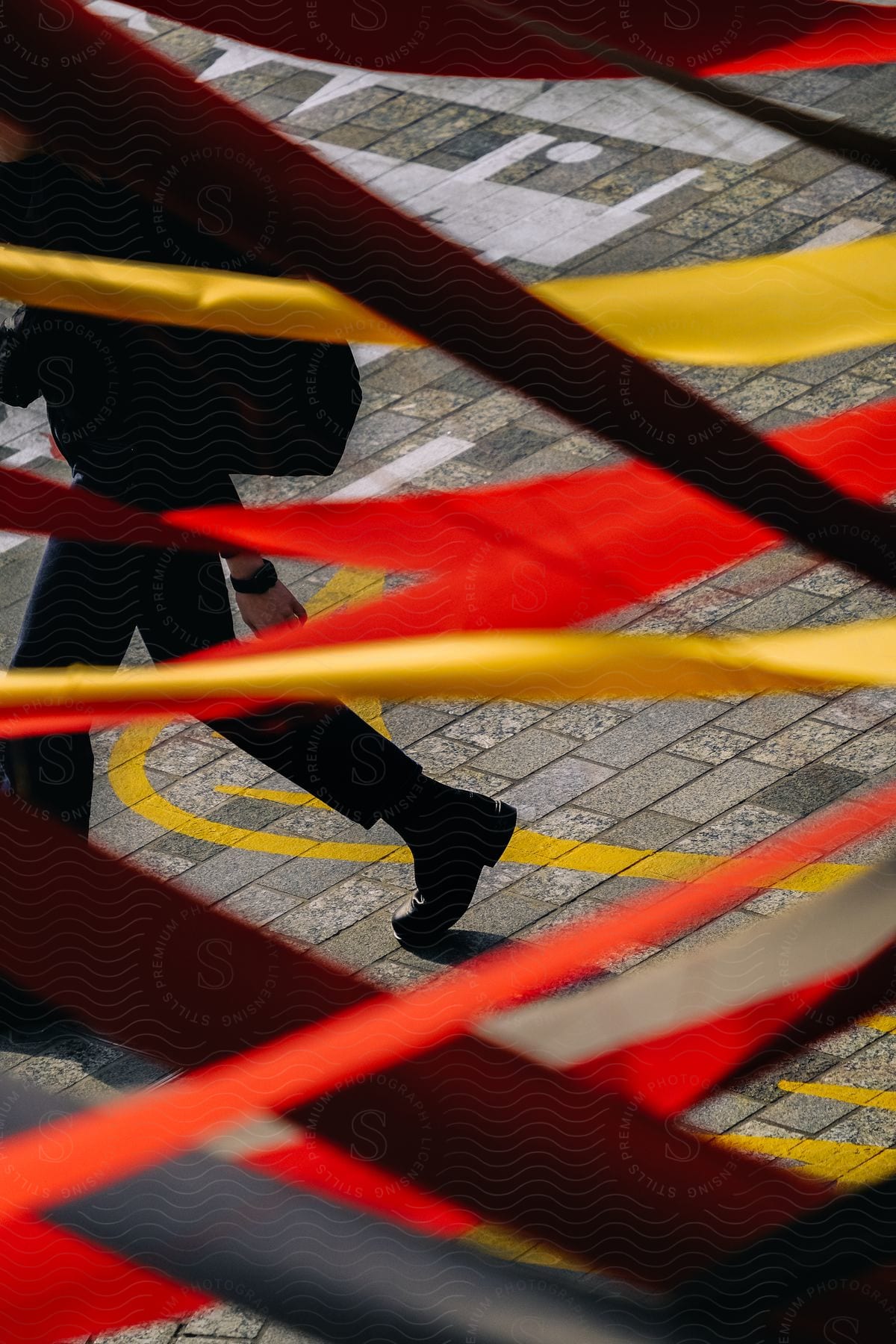 A person walks behind red and yellow ribbons streamed back and forth