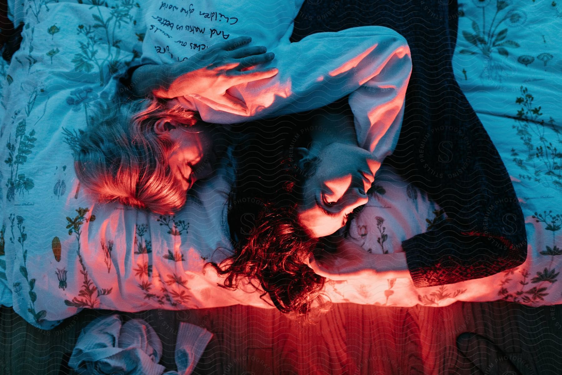 Stock photo of a young couple cuddles in bed under red lights