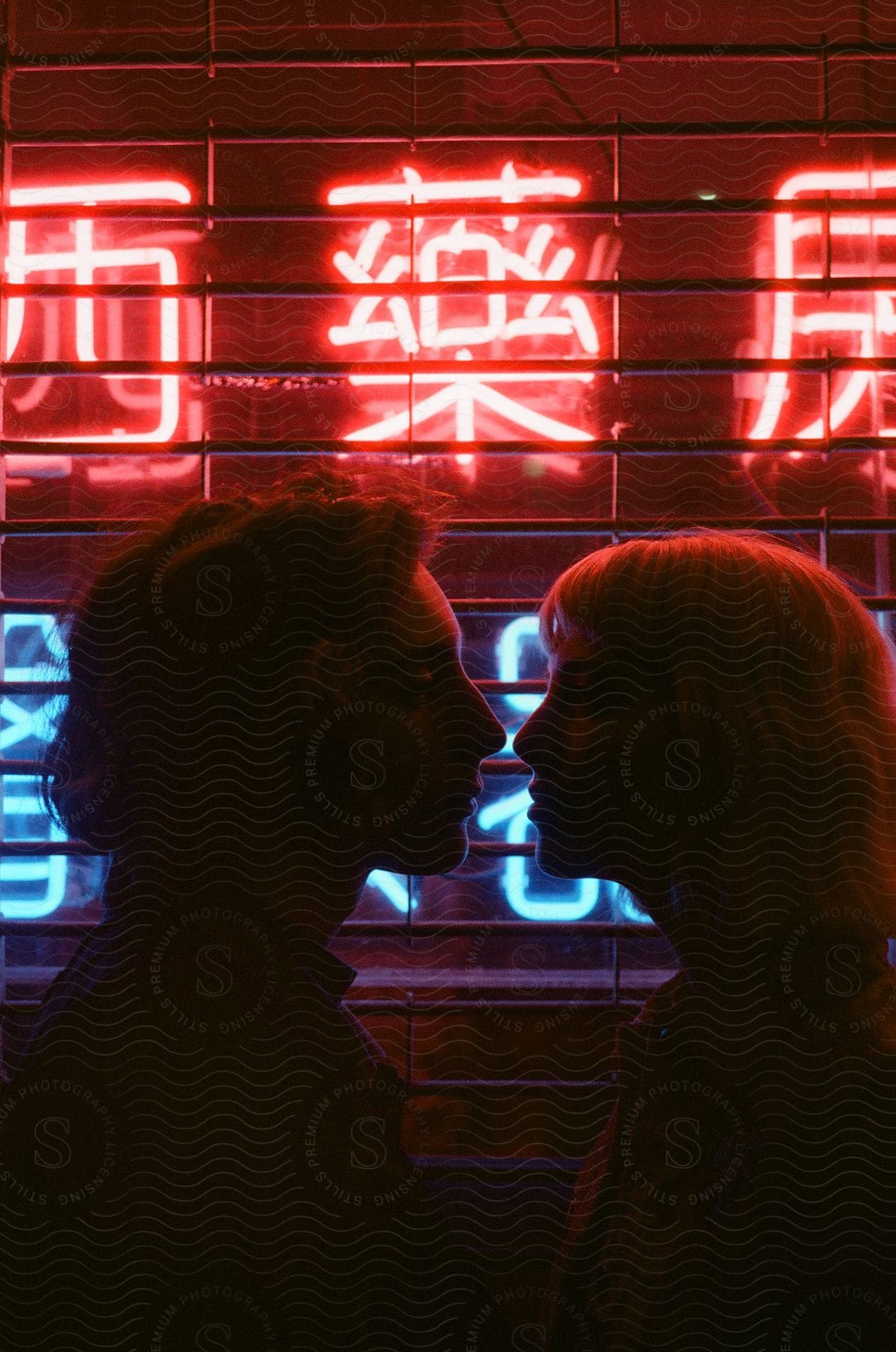 Two happy people in an urban city at night with neon lights and a computer monitor in the background