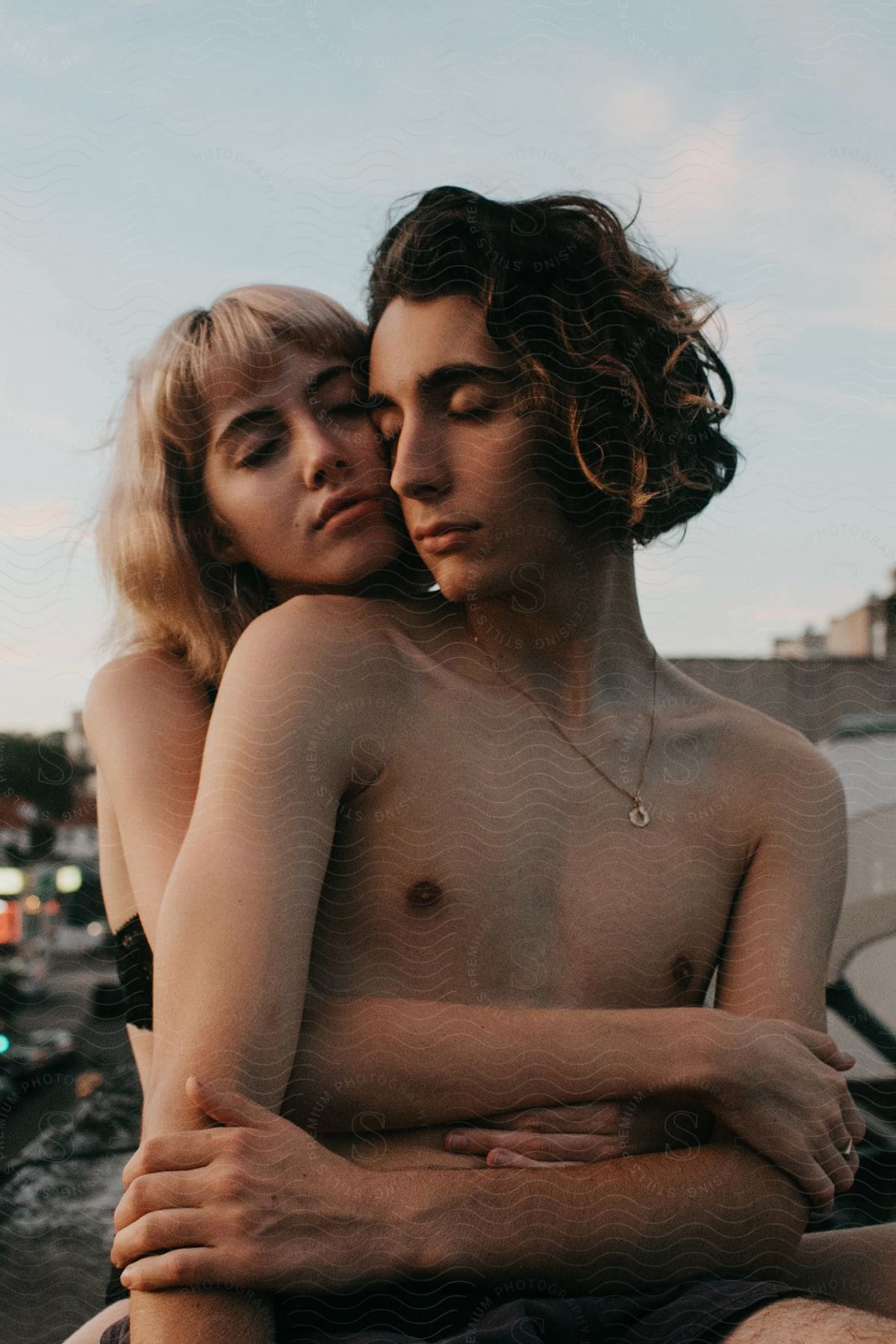 A woman hugs a man from behind on a rooftop at sunset in brooklyn