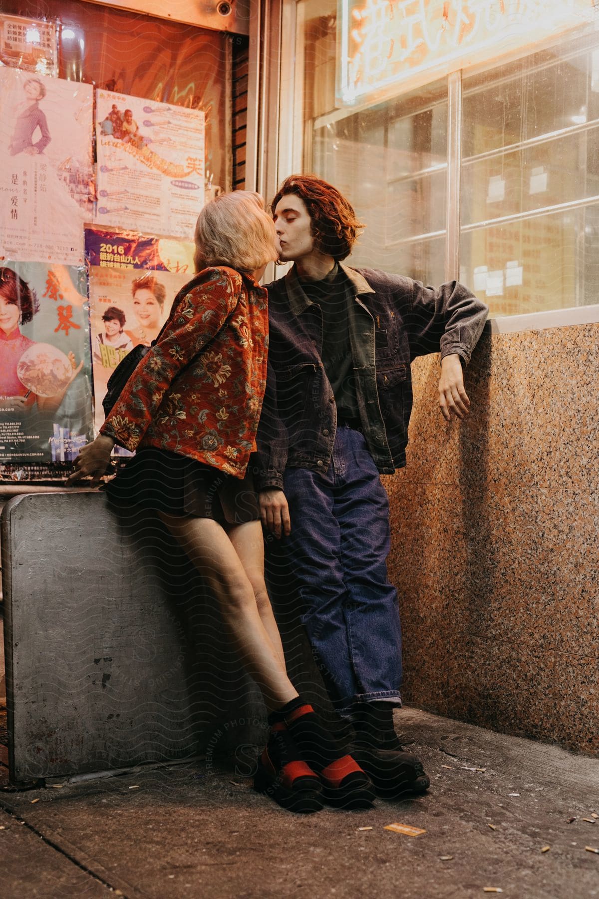 A man and a woman passionately kiss against a building wall at night in brooklyn