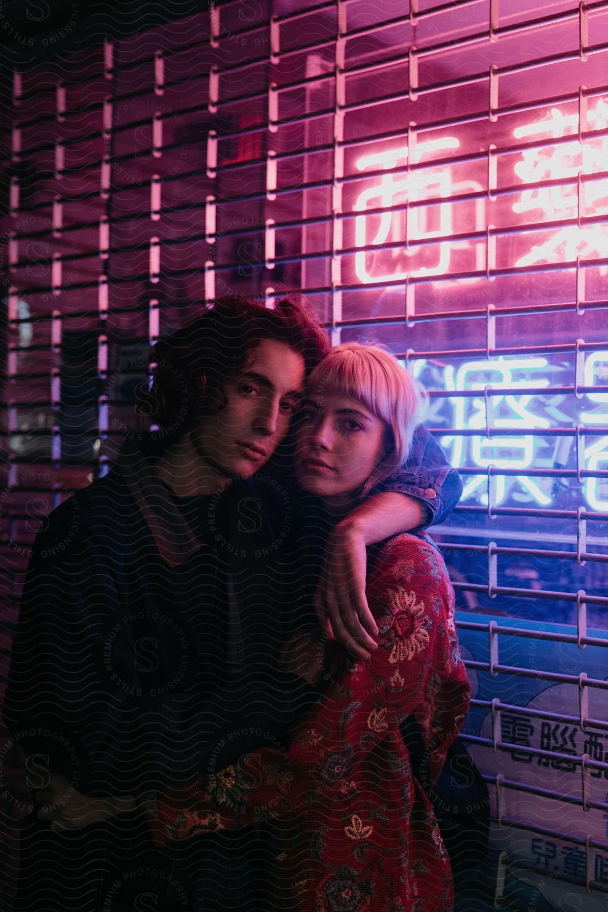 Two happy people in urban brooklyn at night dressed in formal wear with purple lighting and a brick backdrop