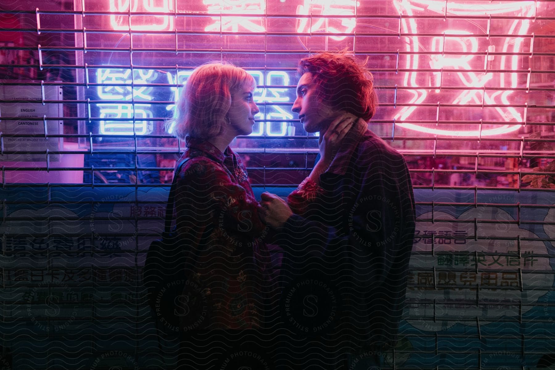 A couple stands in front of a business with neon signs lit inside at night