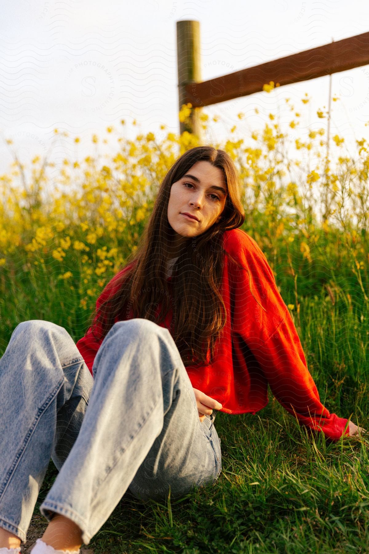 A teenage girl sitting on the grass near yellow flowers