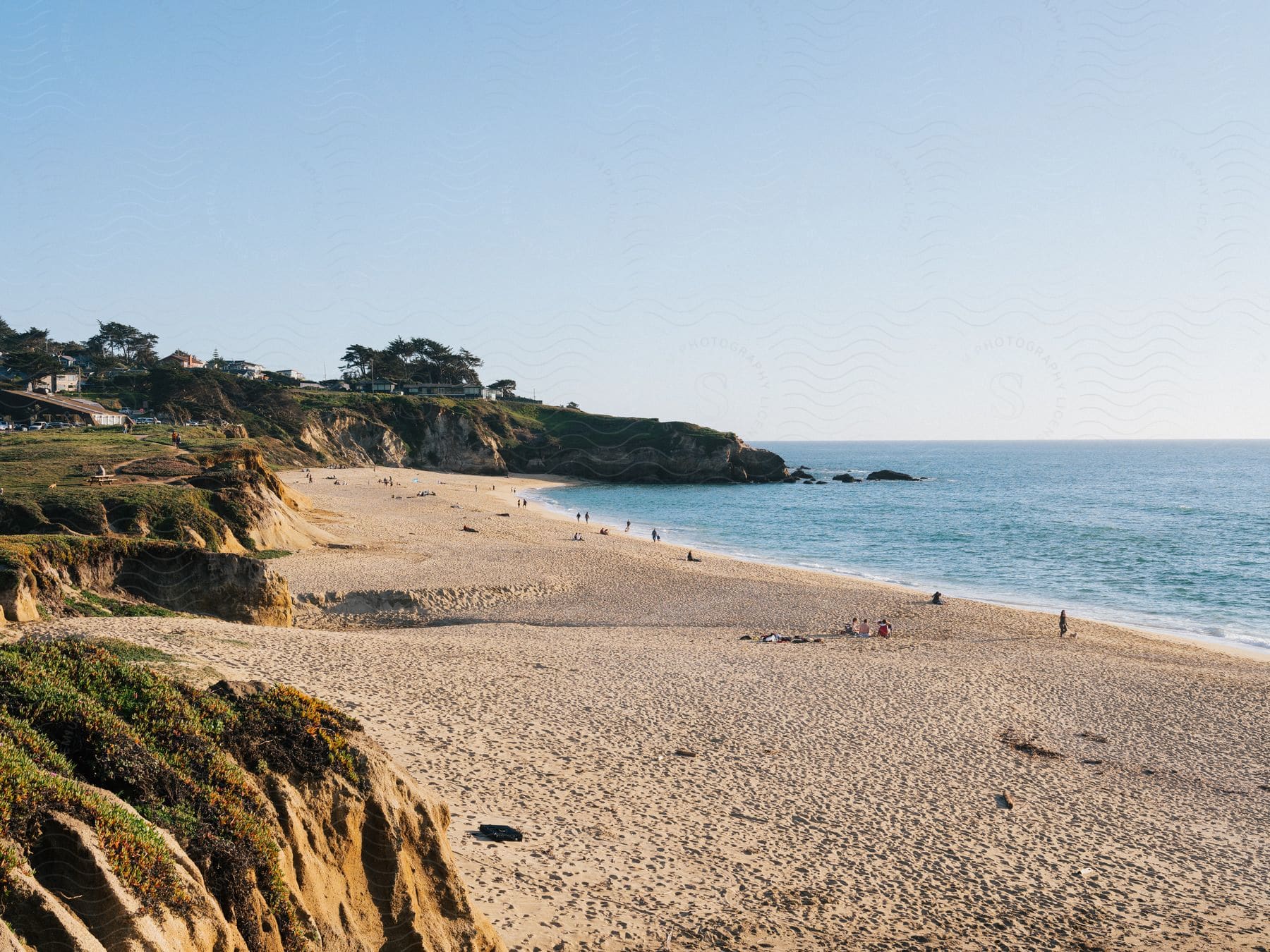 A beach with rocky cliffs and houses on top of them