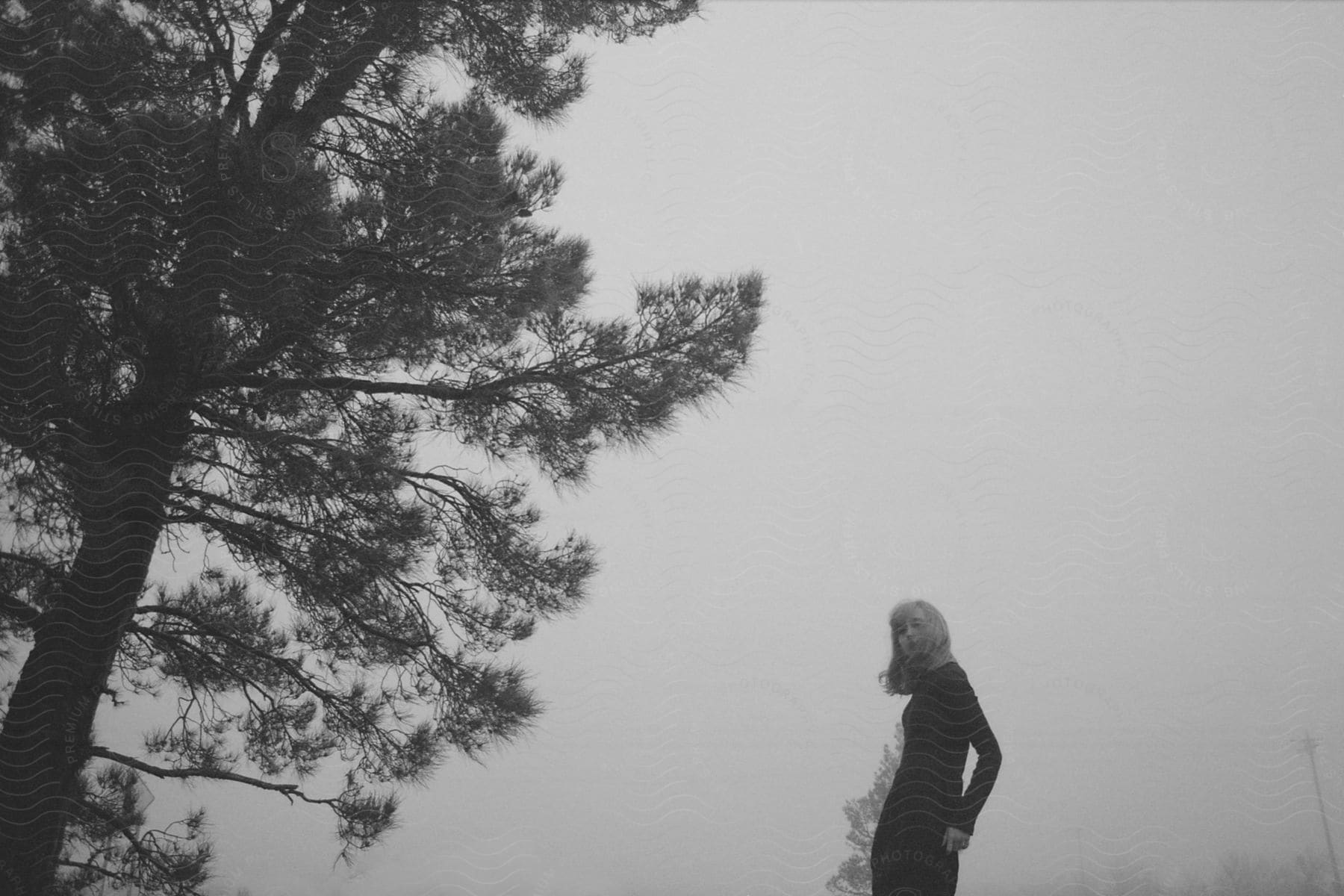 A woman standing near a tree in a black and white photograph