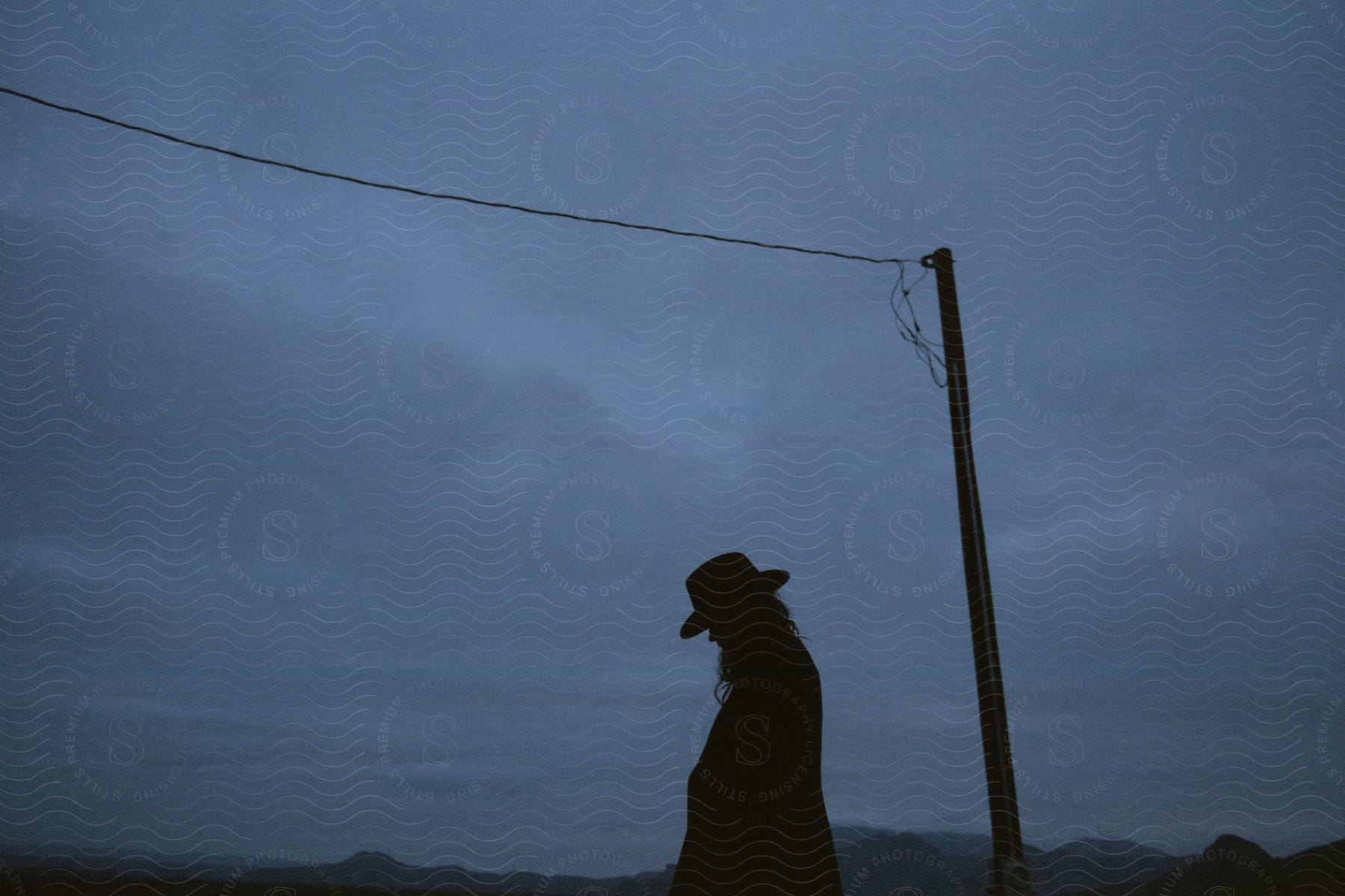 A man standing outside near a telephone pole on a cloudy gray day