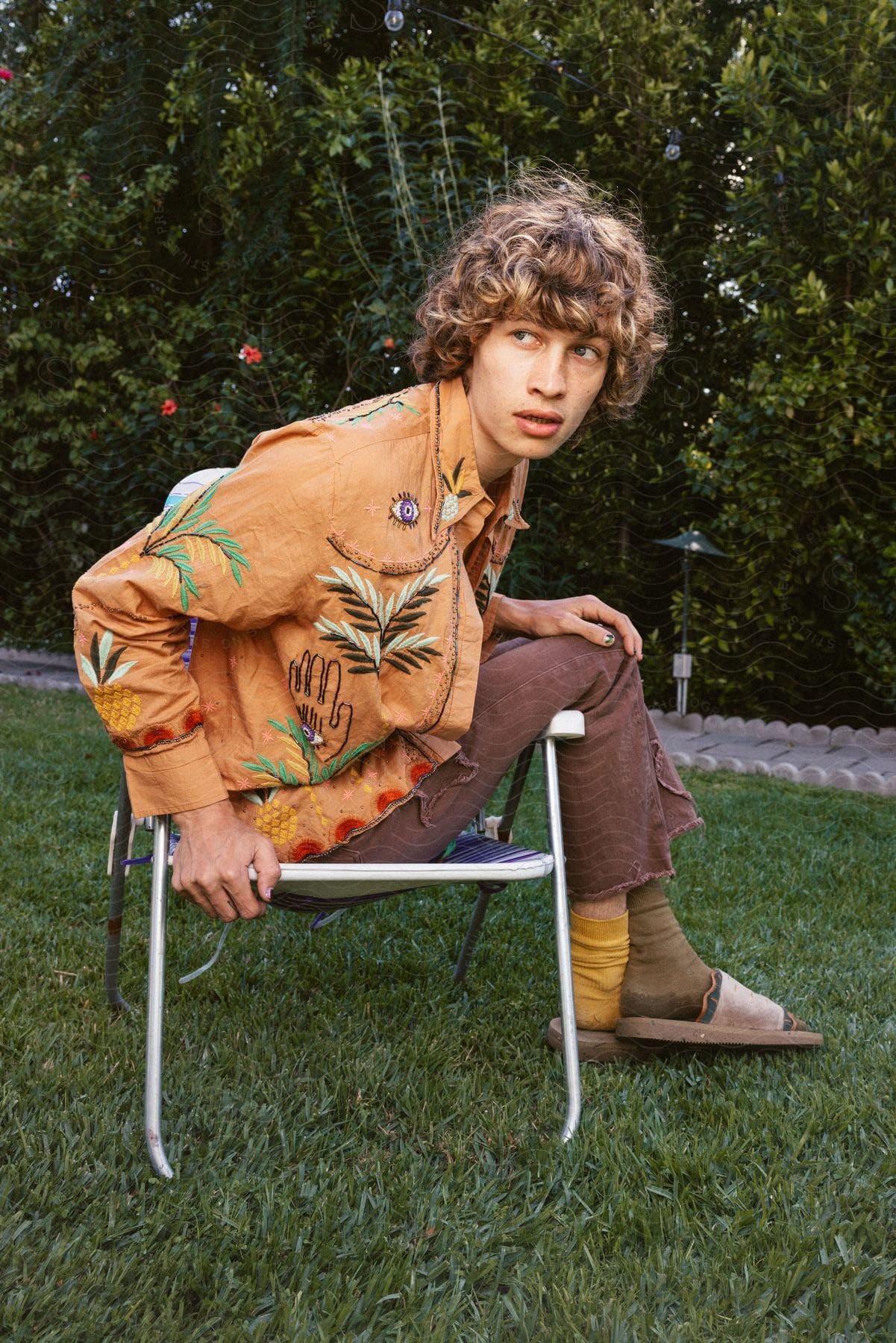 A person with curly hair lounging on a folding chair in nature