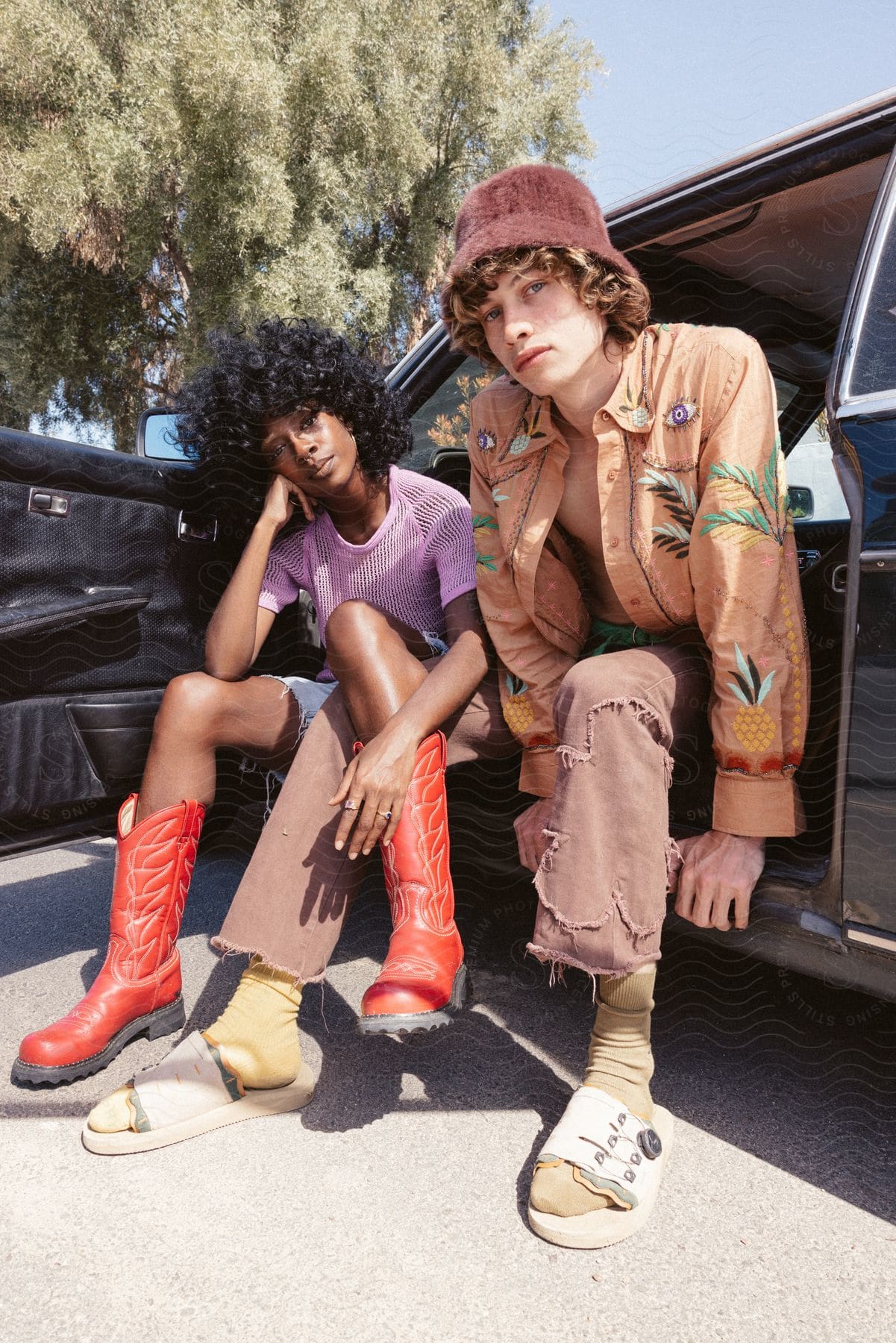 Two people a male and a teenager are happily lounging outdoors in los angeles wearing fashionable clothing and showing a carefree attitude