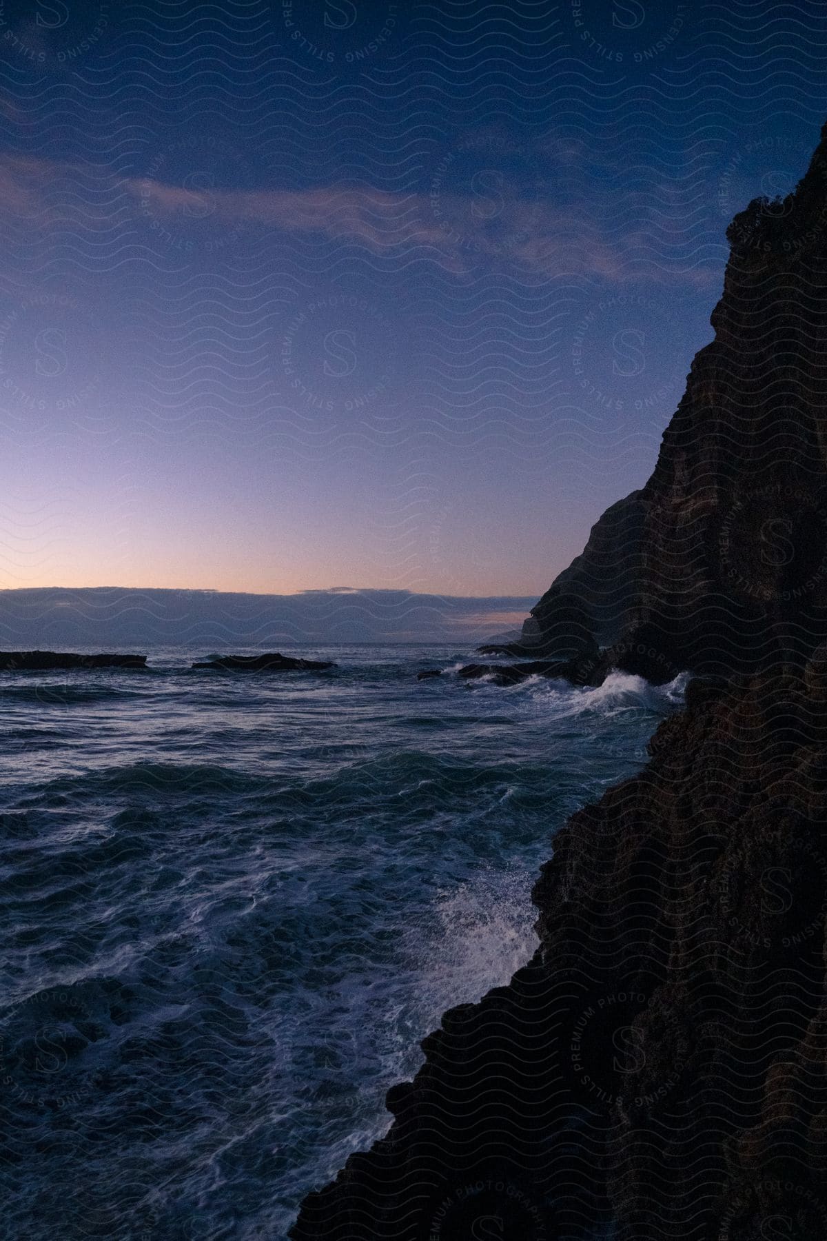 Brown mountains and small waves in the ocean are depicted in this image of the beach