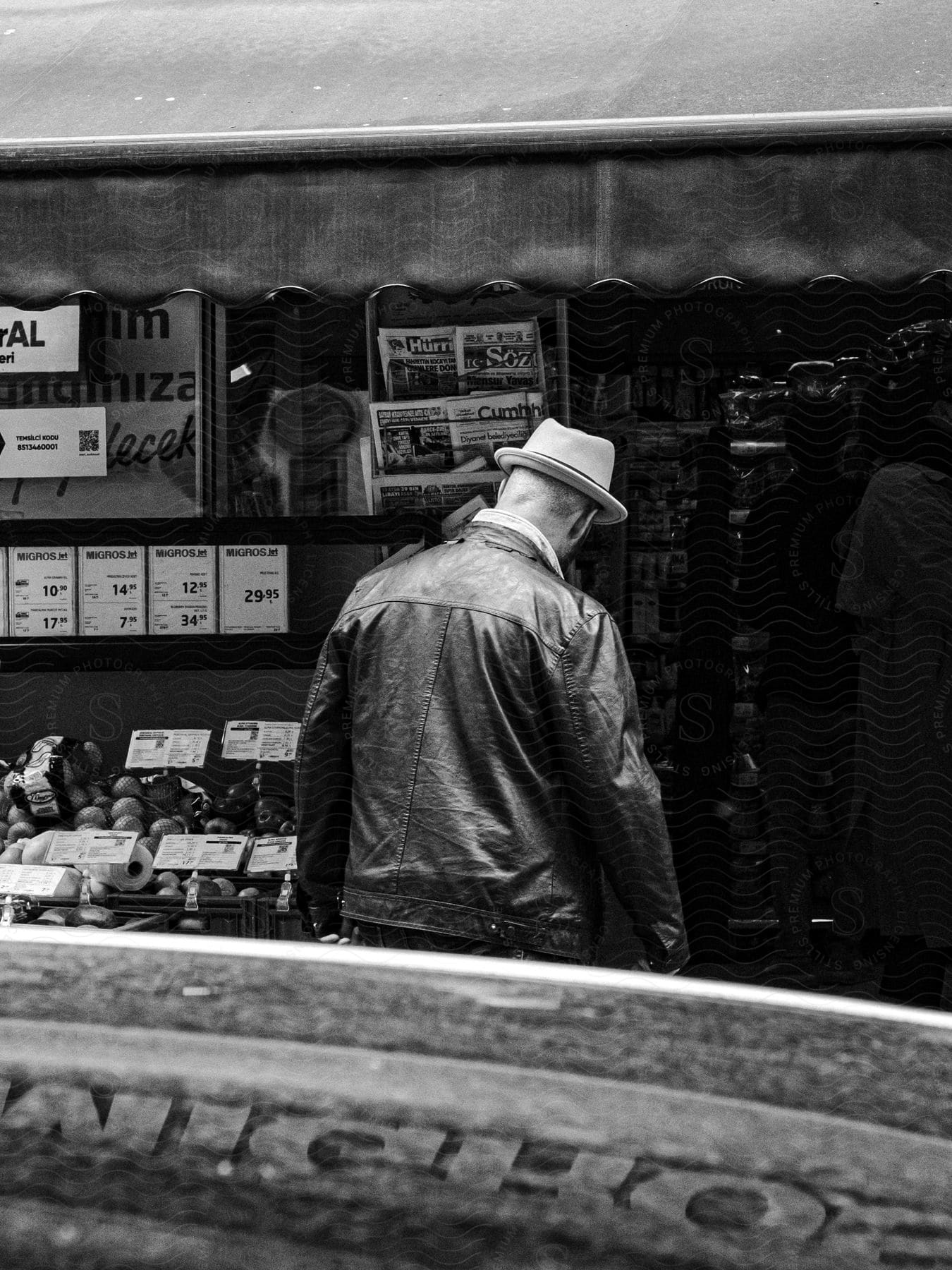 A man walks into a shop selling items like newspapers and vegetables