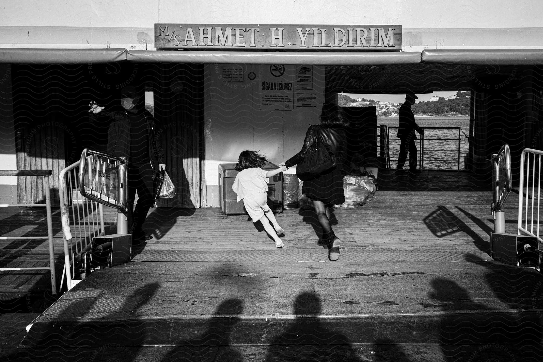 A mother and daughter hold hands and run out of a building with shadow people standing behind them