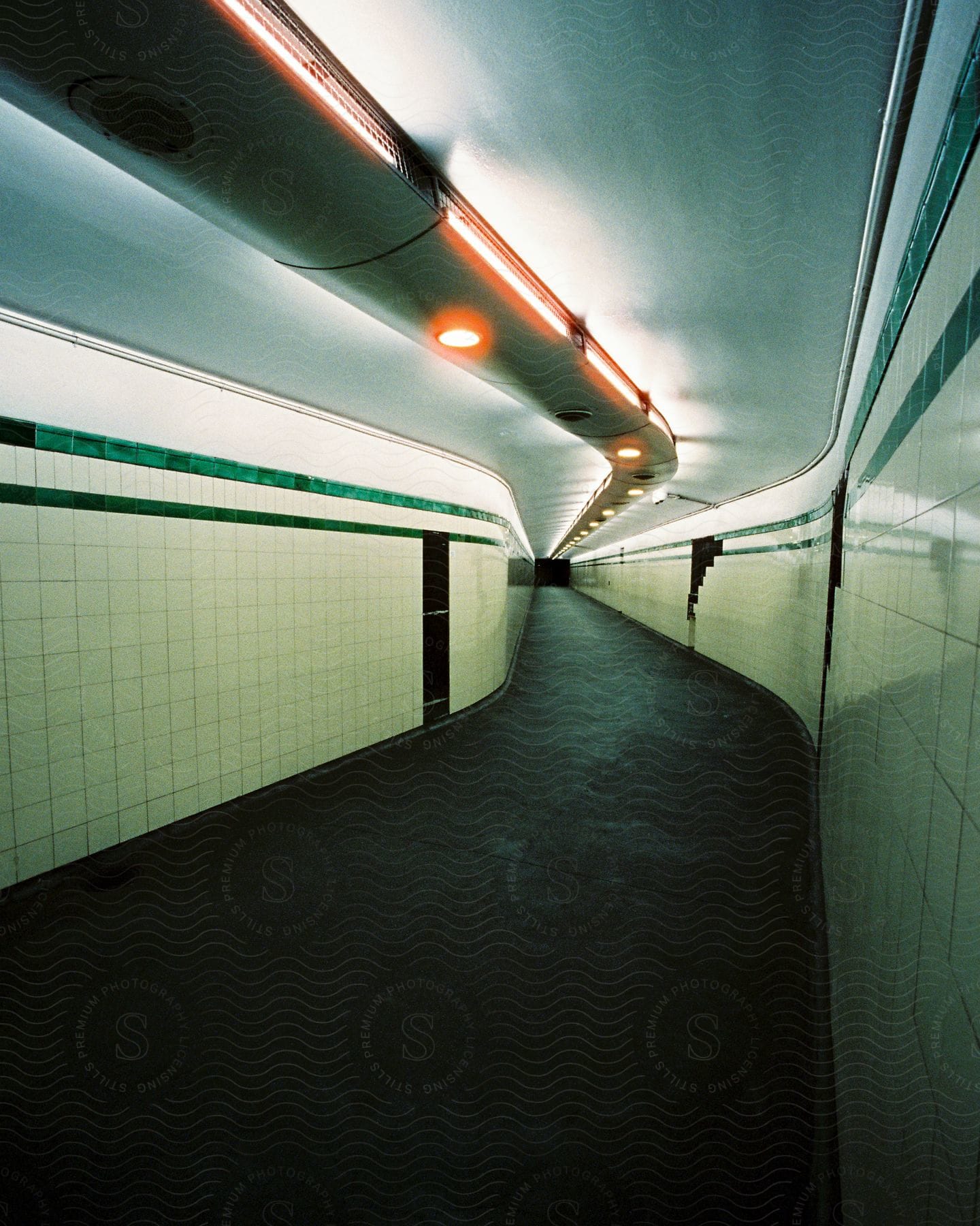 Long corridor with black floor and white tiled walls inside a building