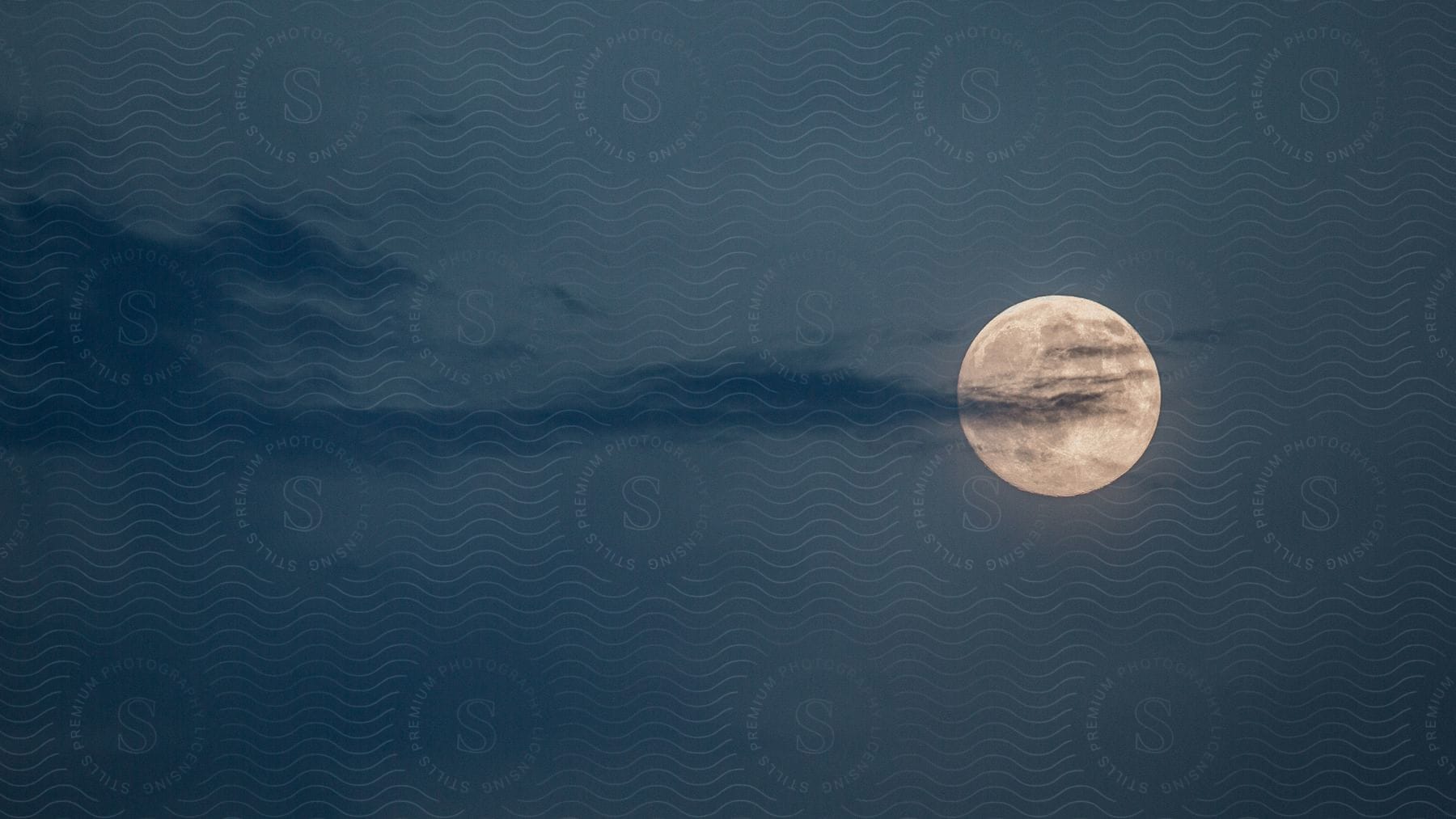 A full moon with a strip of clouds in front of it