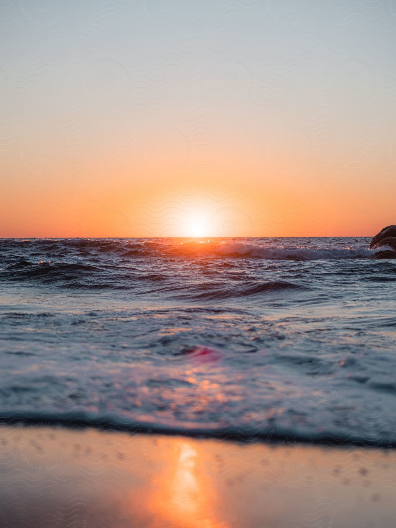 A sunset over the ocean with the sun reflecting on the beach