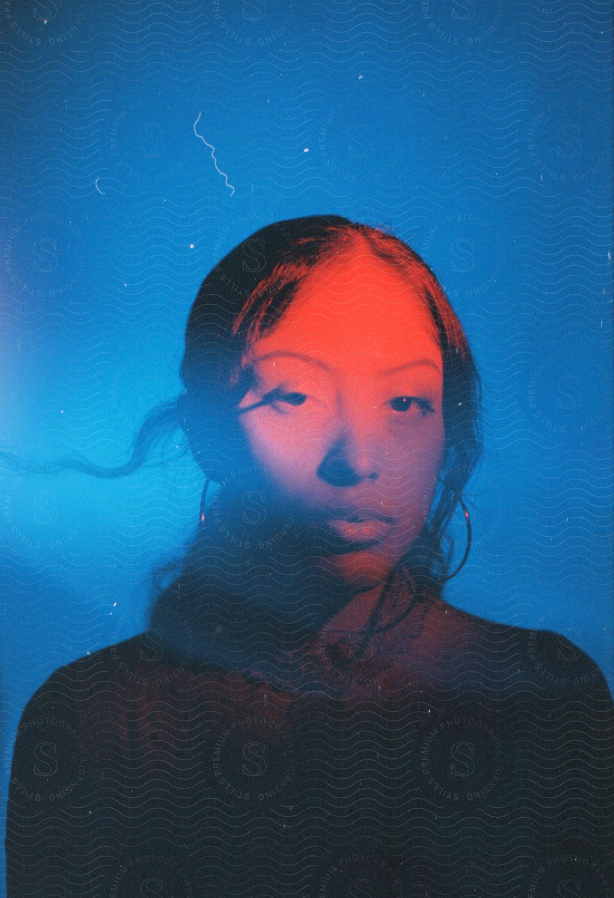 WOman with wavy hair and hoop earrings in red and blue lighting