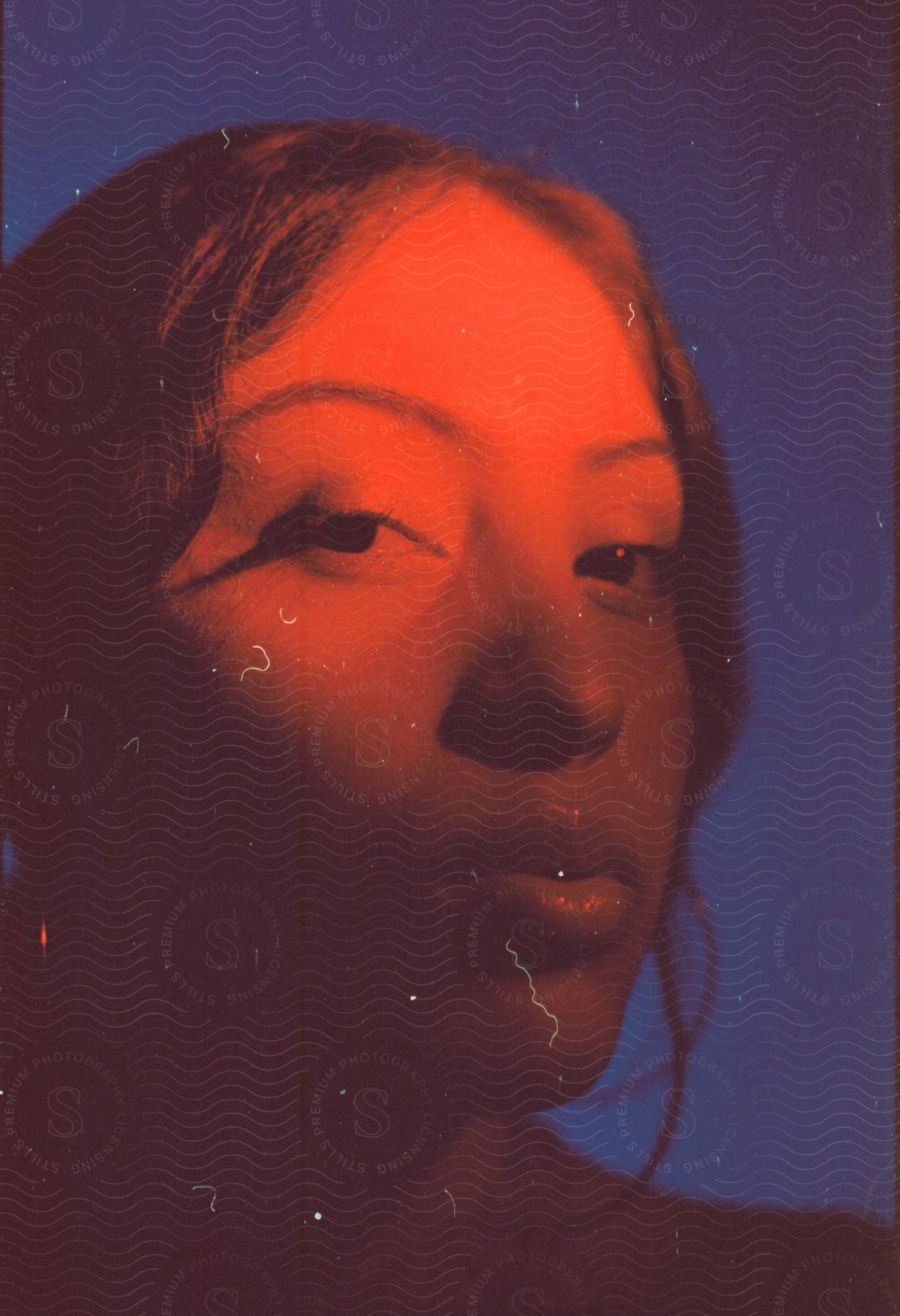 A woman with lush wavy brown hair, full lips, and prominent hoop earrings fixes her gaze intently on the camera