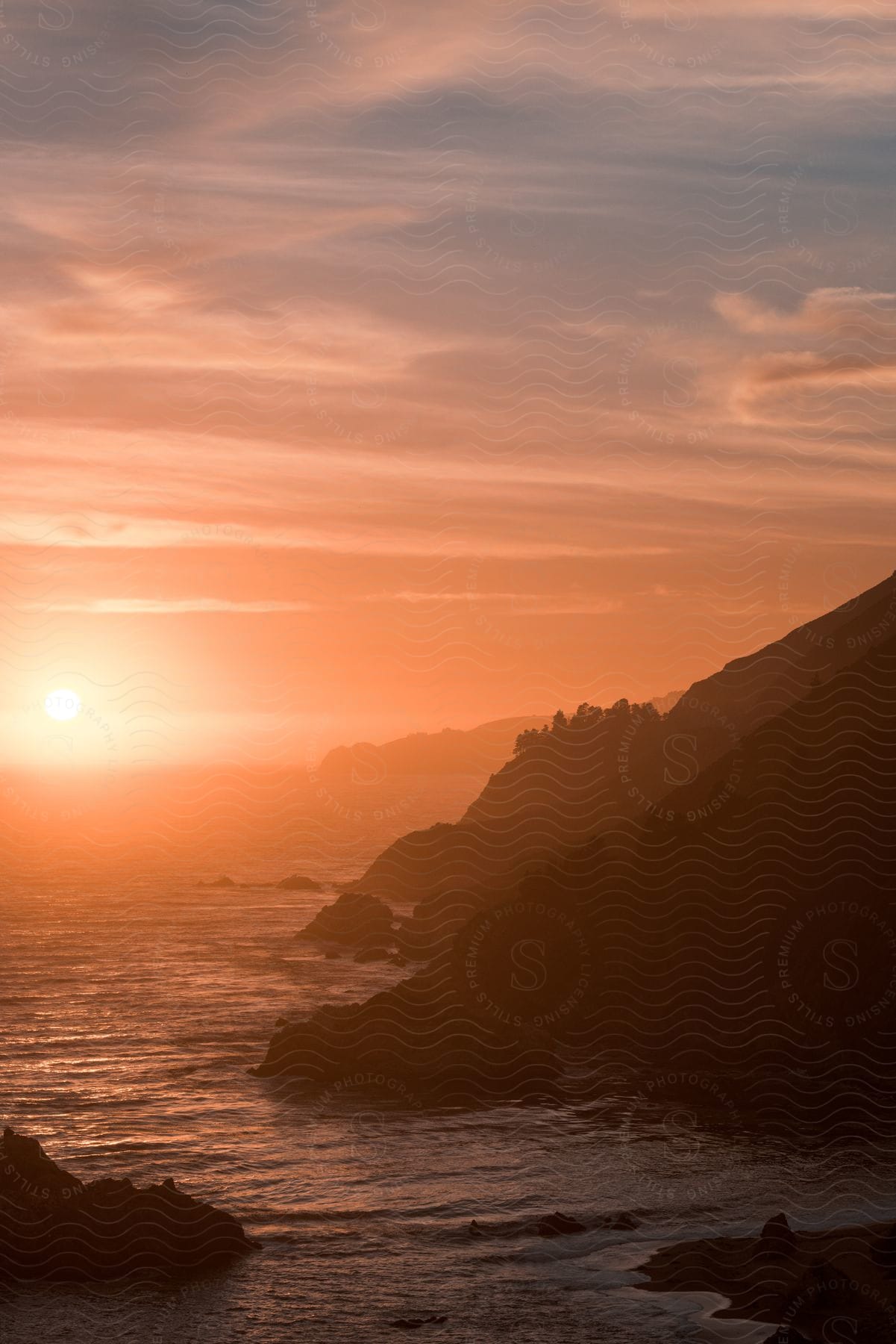 A sunset near the ocean and mountains at dusk