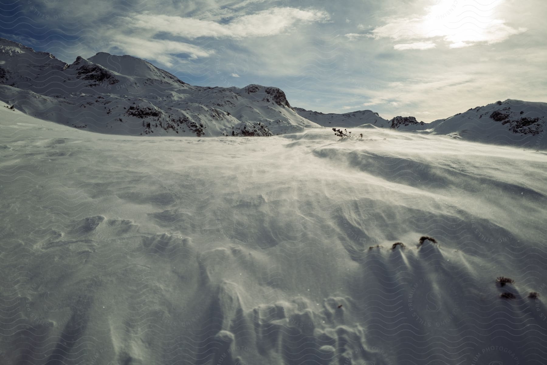 Mountains in the distance under a cloudy sky seen across drifting snow