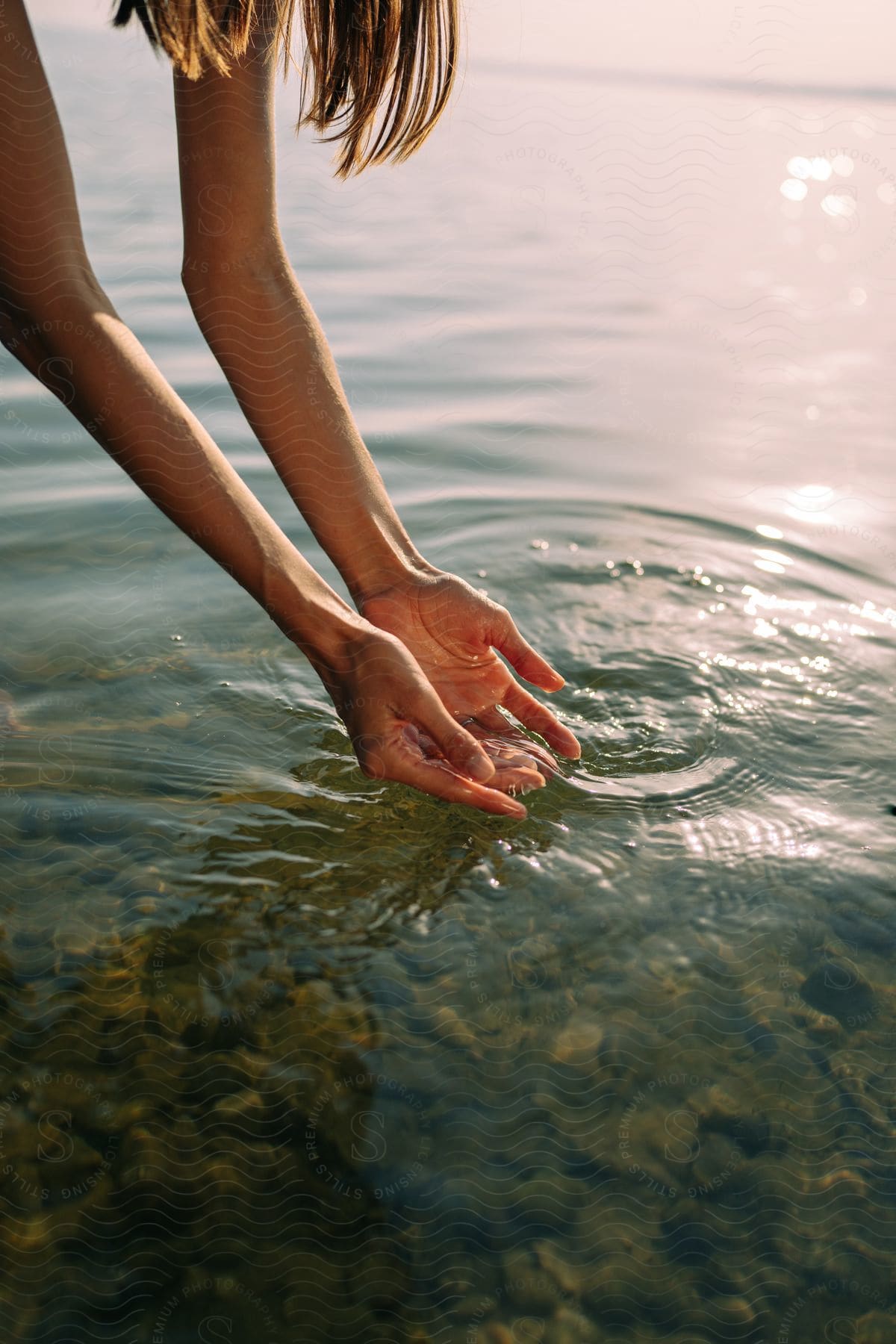 A woman washing her hands in a river with stones