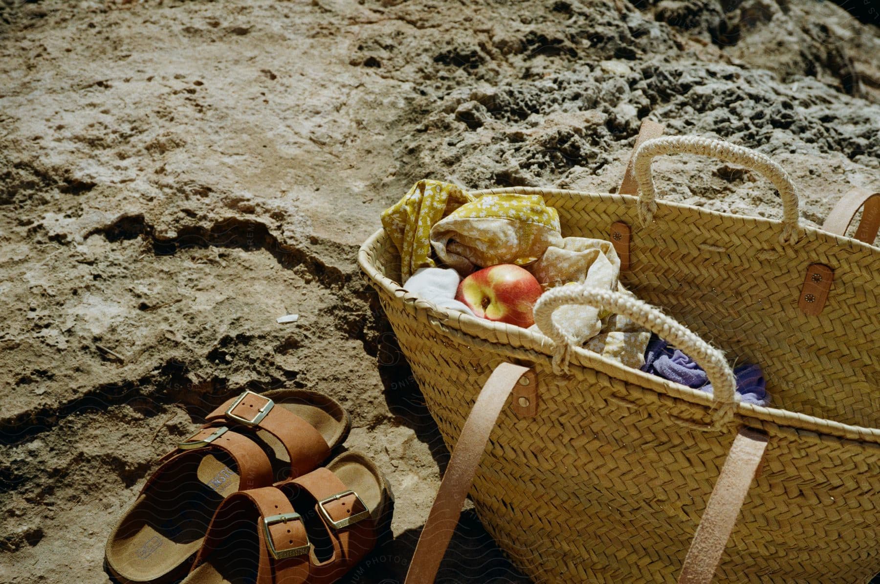 Beach basket with clothes apple and sandals on sunny day