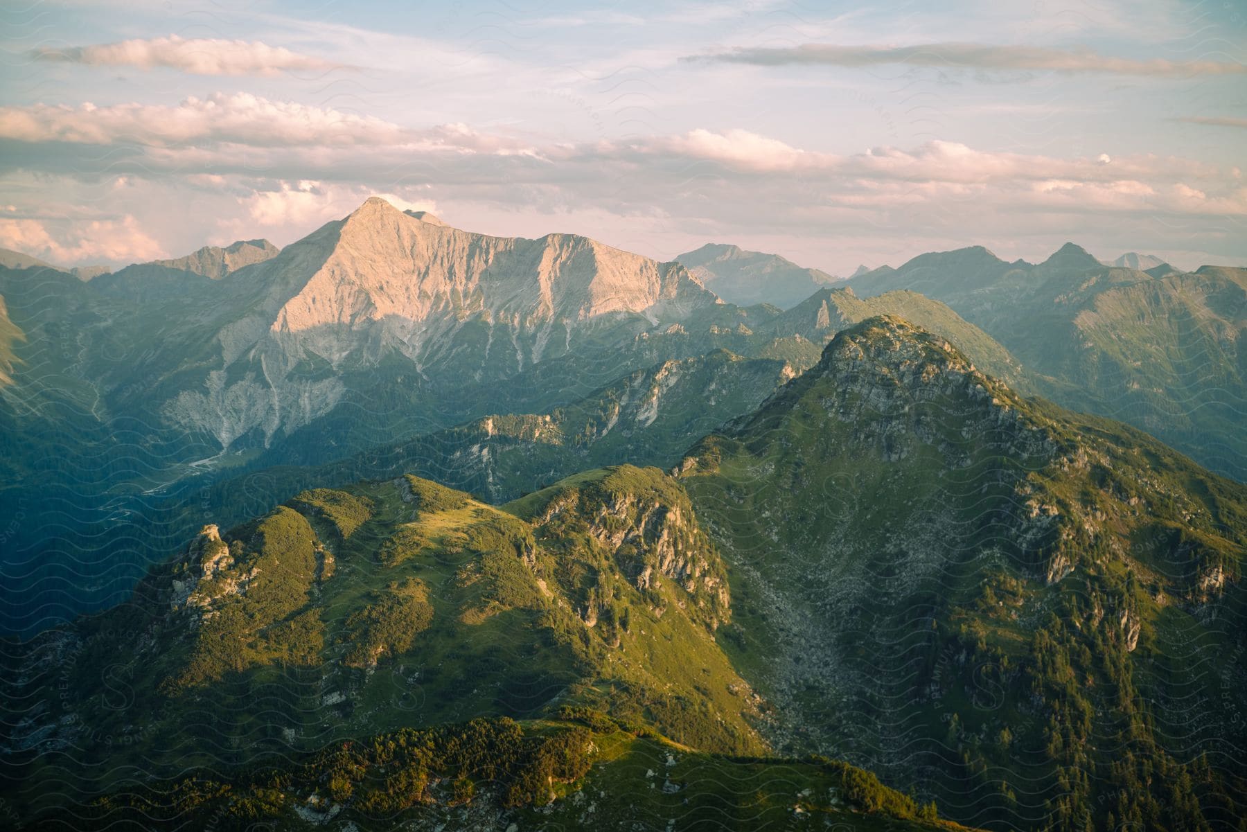 A green mountain range under a cloudy sky with hills and valleys