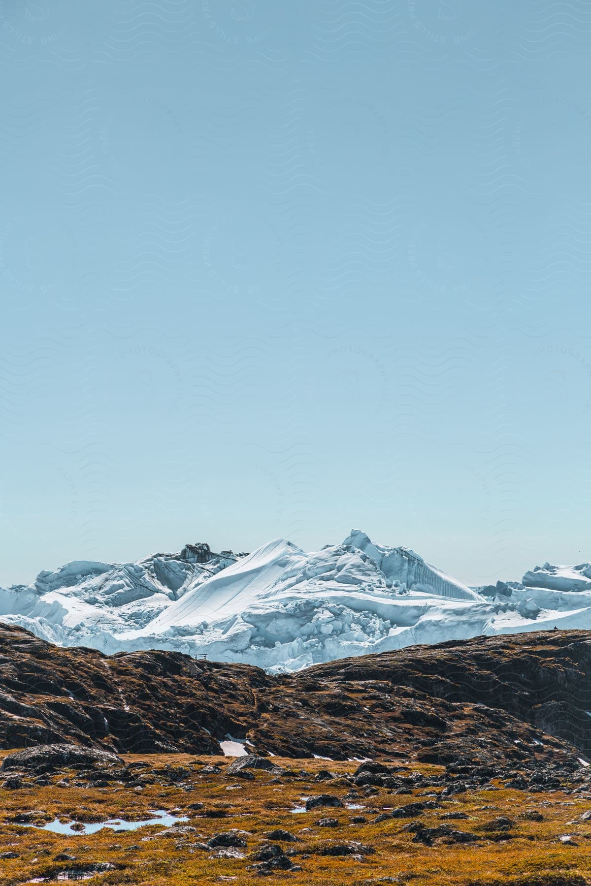 A serene mountain landscape in greenland with snowcovered peaks and a clear sky