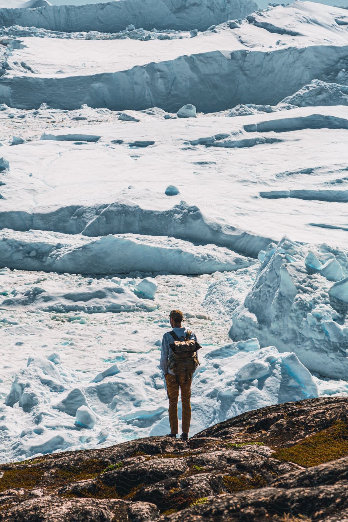 A man standing near a mountain with water and snow