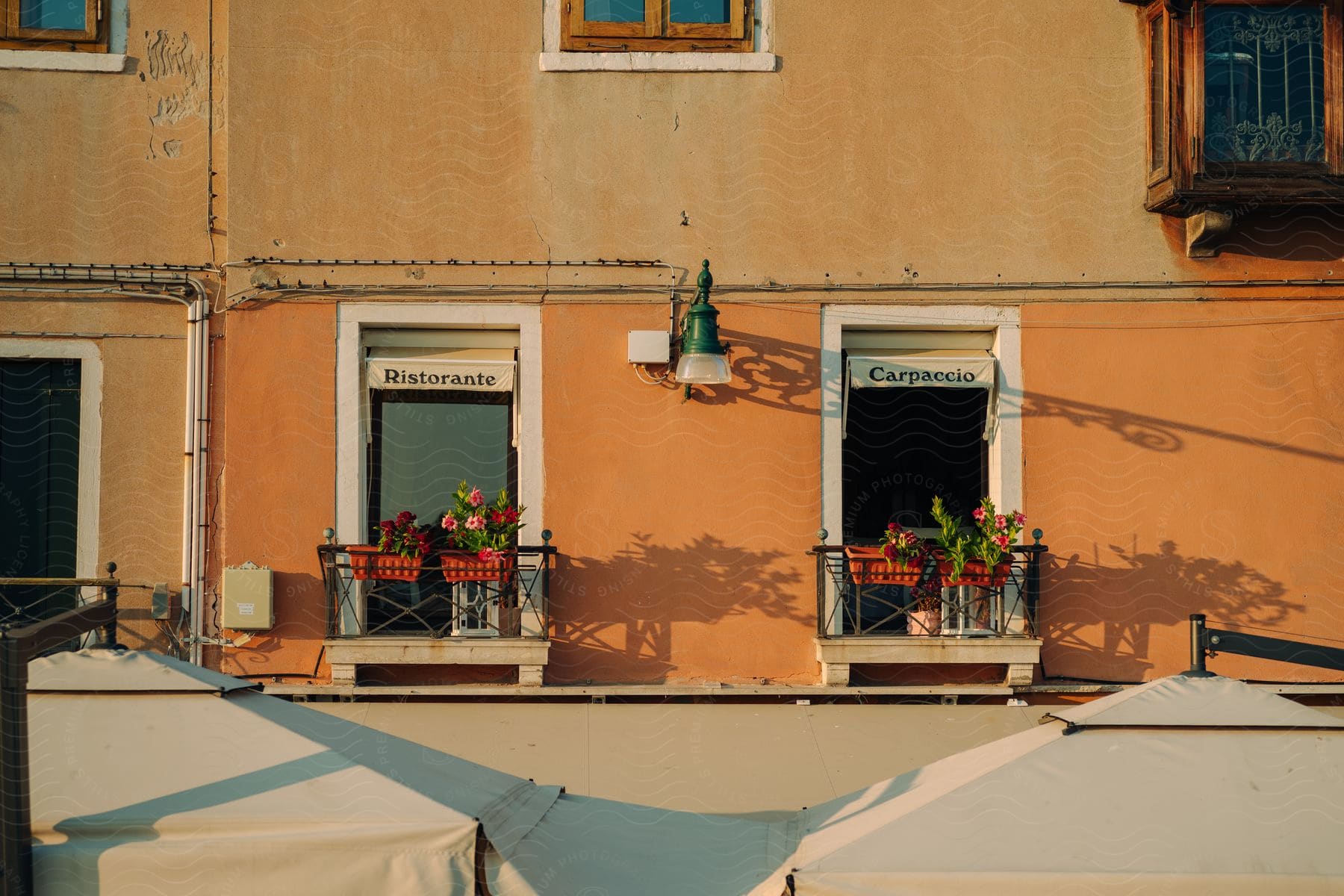 Exterior of an orange painted building with restaurant windows small balconies and hanging planters