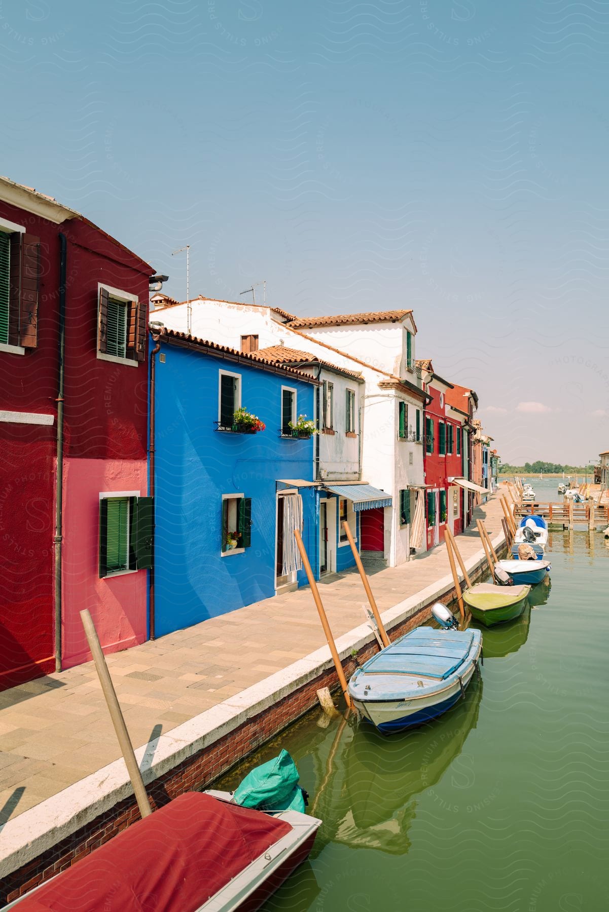 Colorful houses line a path with a lake and canoes in front