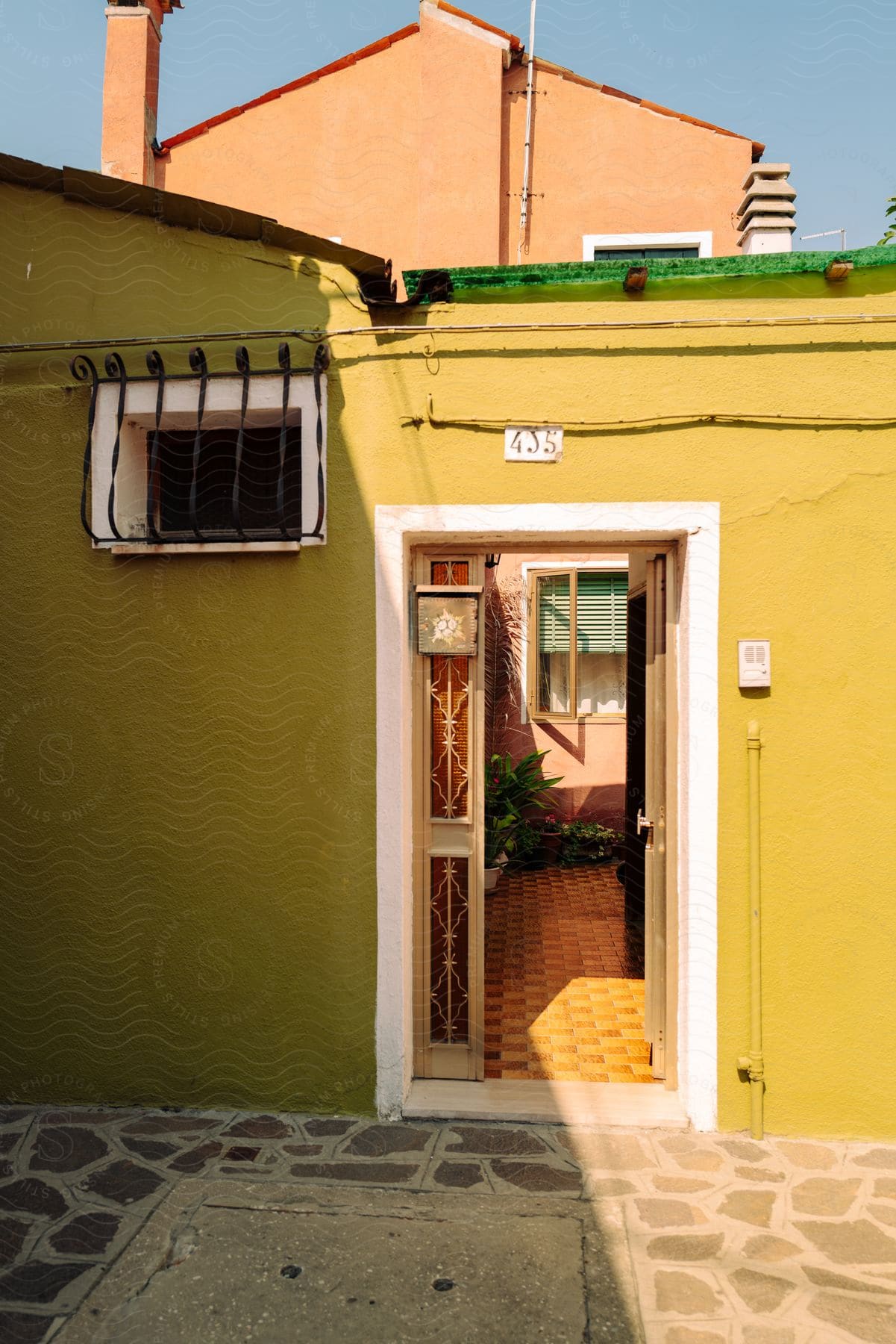 A courtyard seen through the door of a yellow house