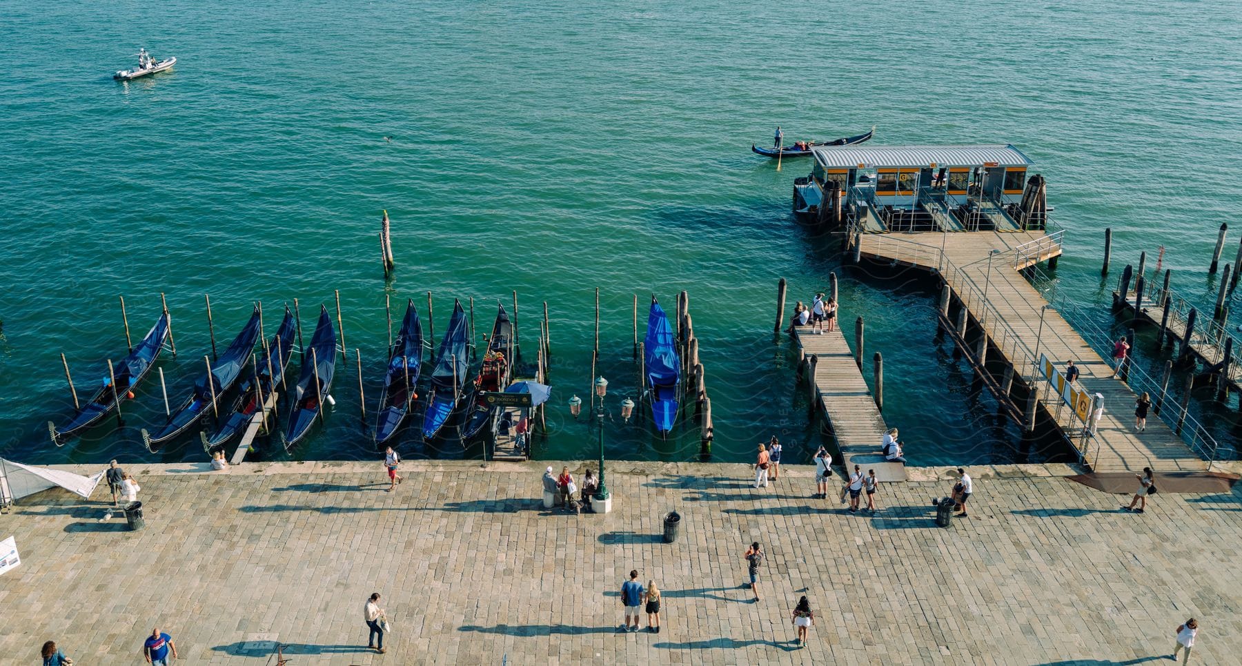 A wooden boating port with eight blue canoes in the water and a small building on the pier