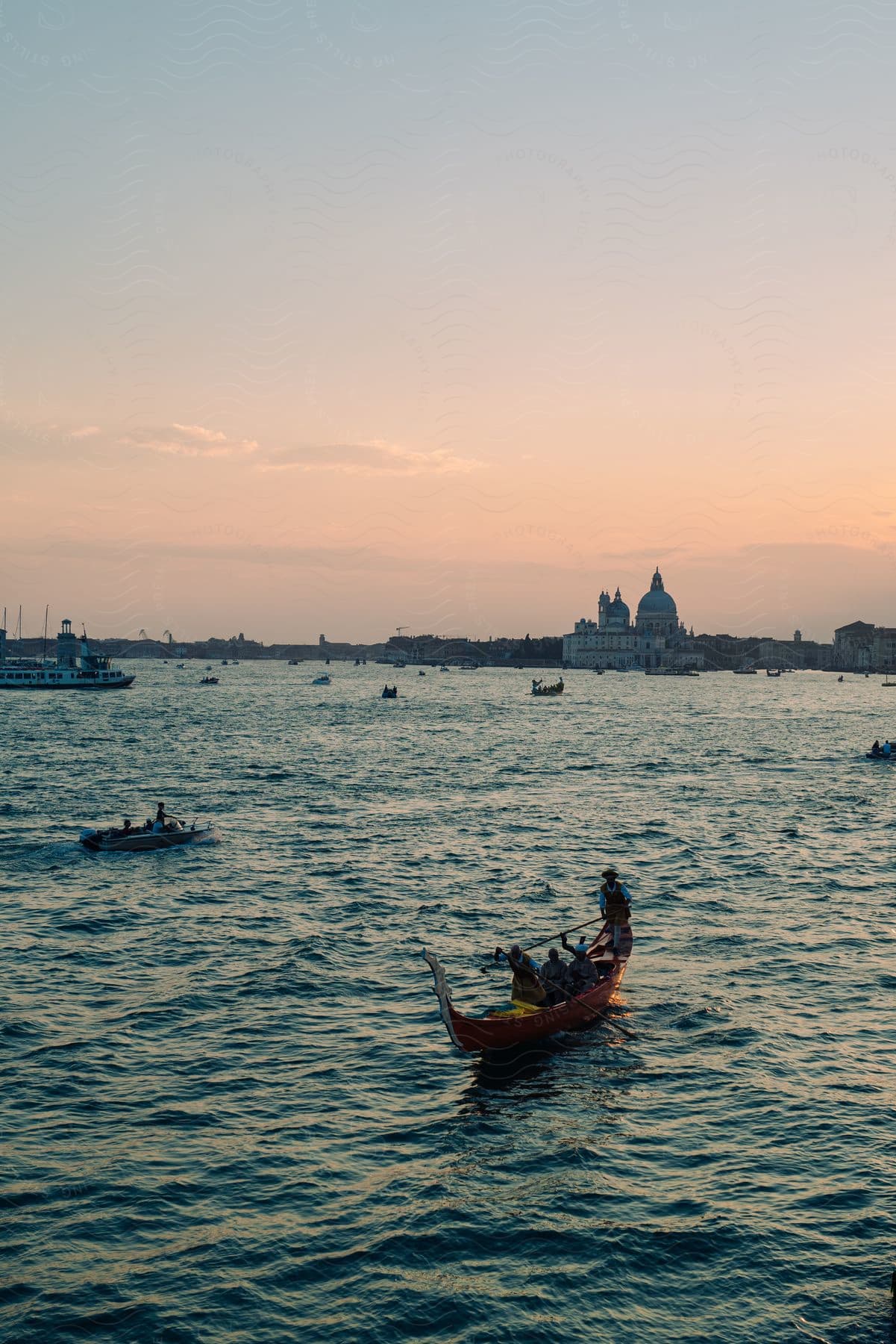 Boats sailing on the ocean at sunset near a city