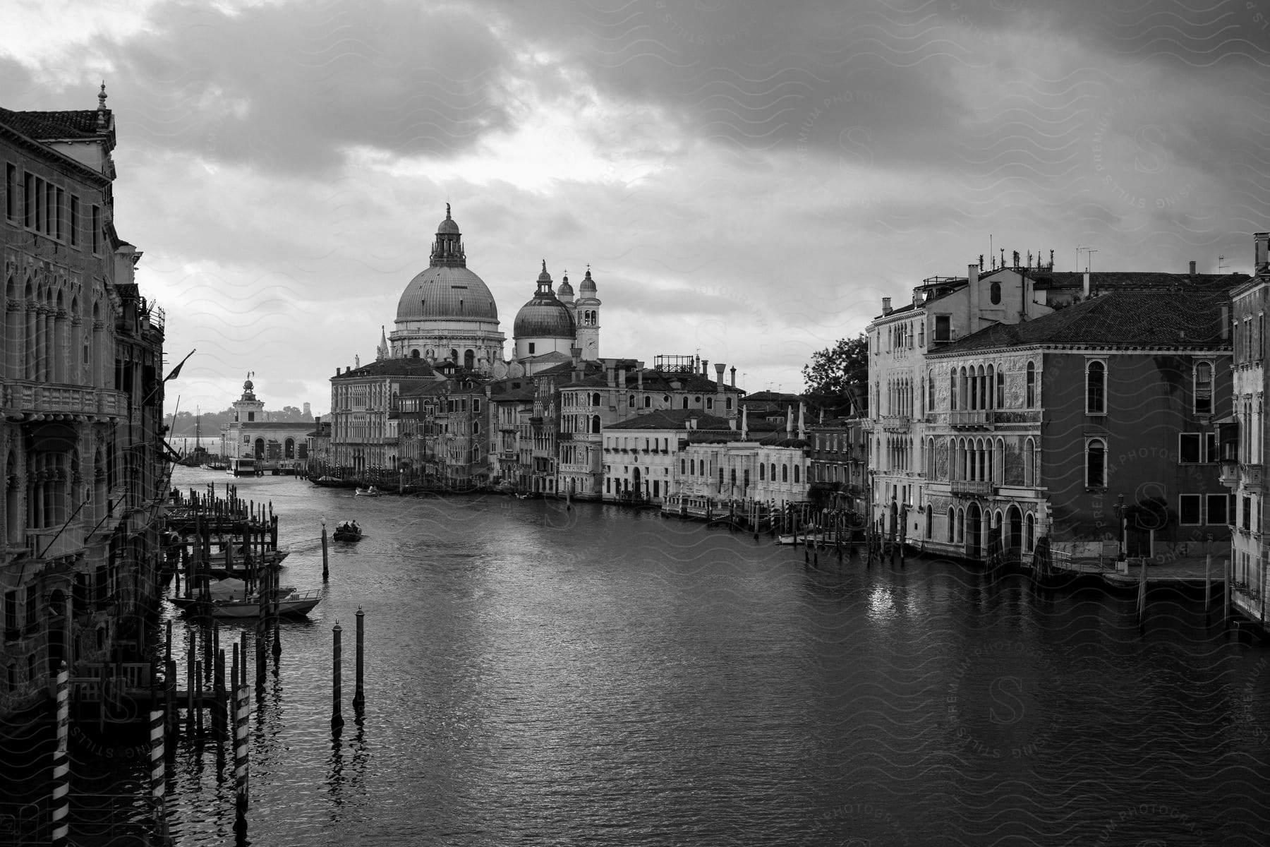 Black and white photo of the canals in venice italy on a cloudy day with little activity on the water