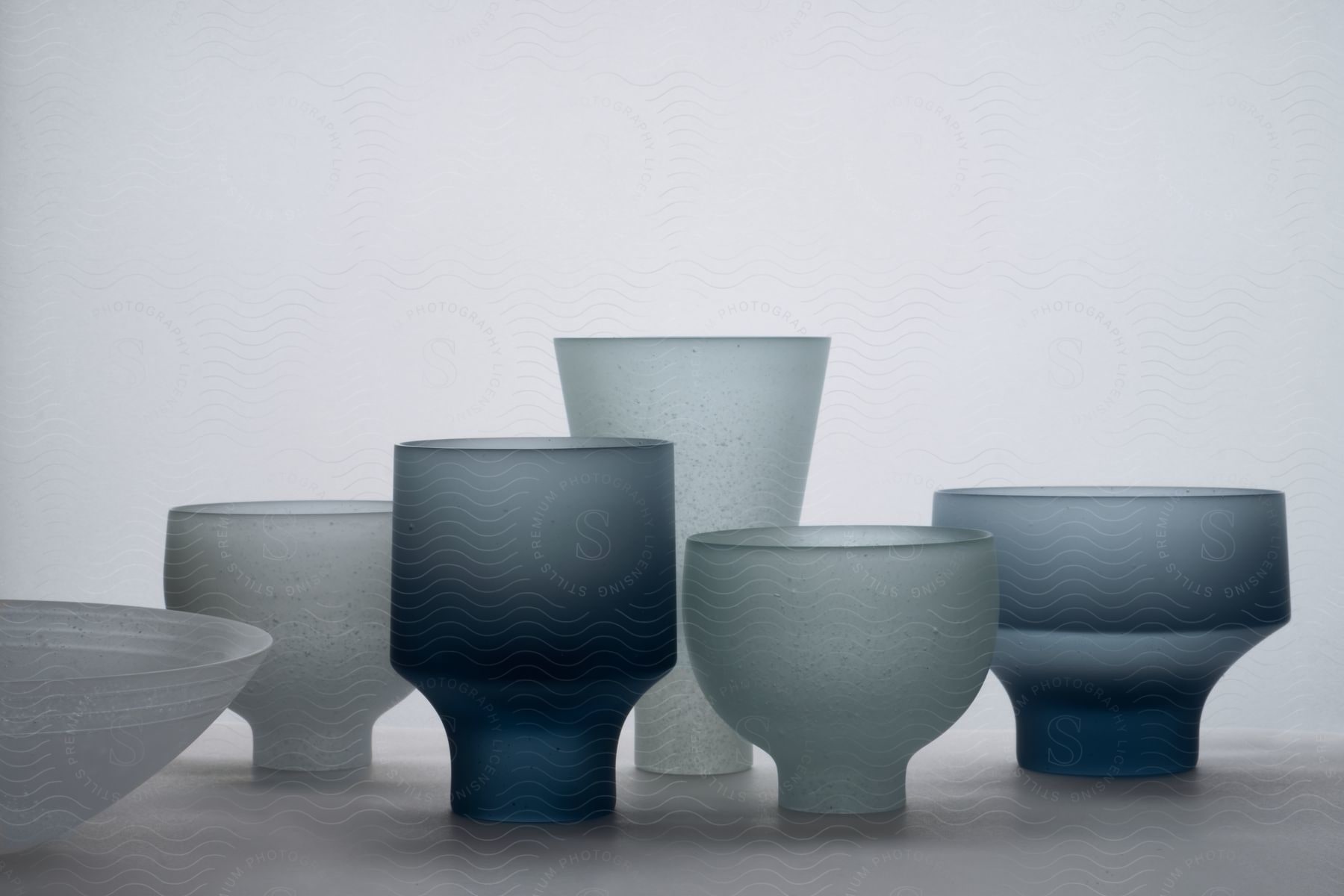 Smoked glass dishes arranged on a table with a grey backdrop in a studio environment