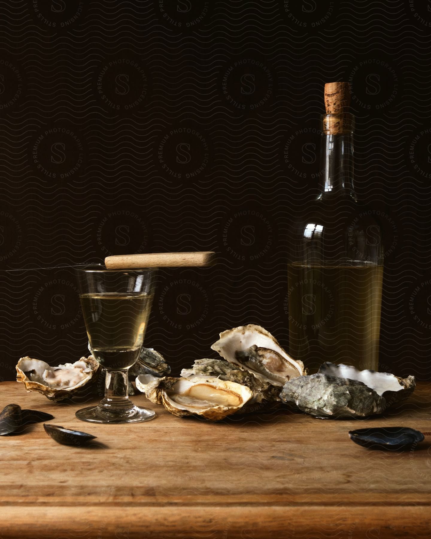 Wine bottle next to oysters and knife on wooden table