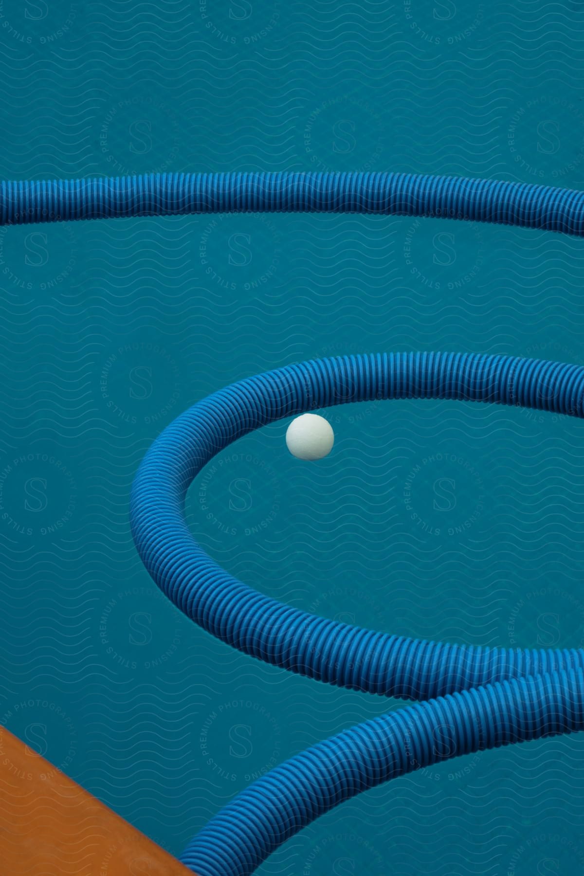 A blue hose curves around a white small ball on a blue surface