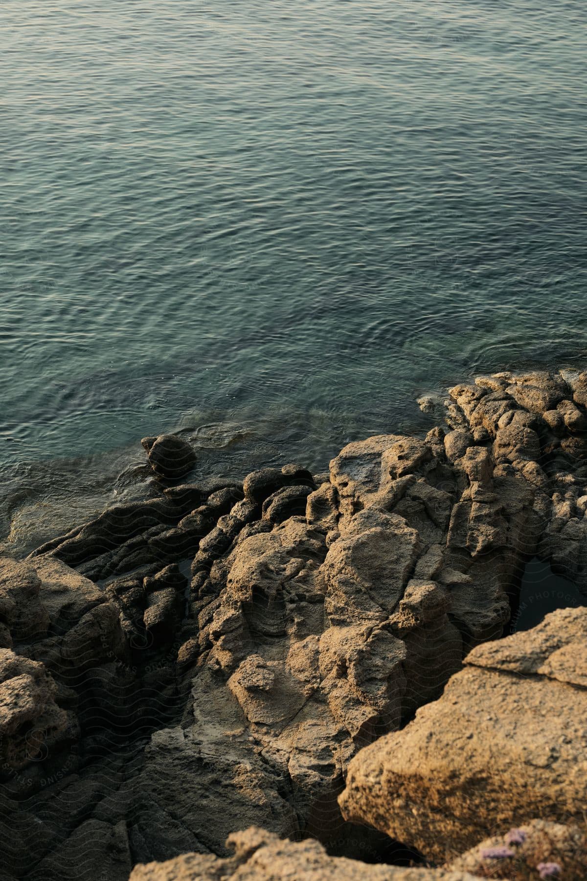 Stock photo of ocean waves calmly ripple against a rocky shore