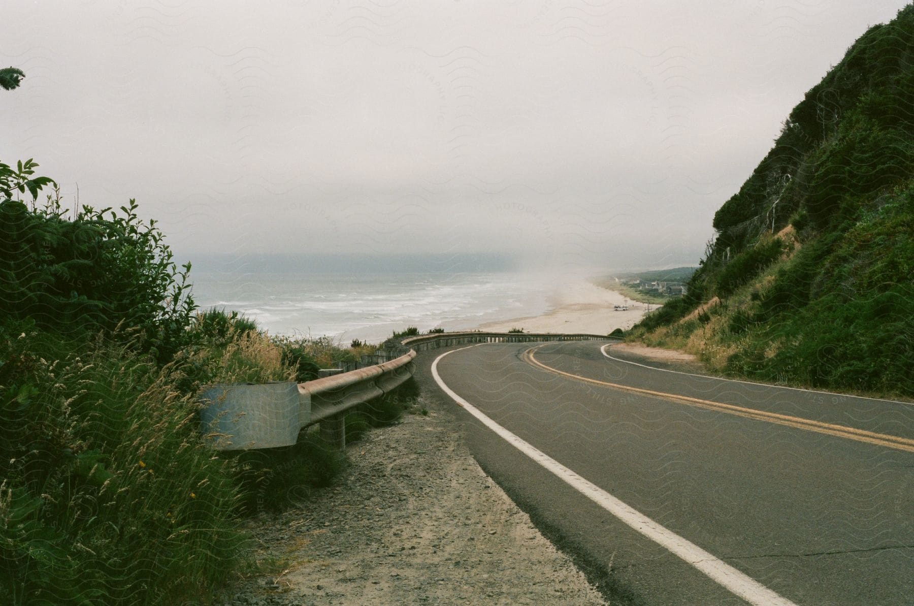 A scenic view of a tiled road winding alongside a beach with mountains in the background blending nature and infrastructure harmoniously