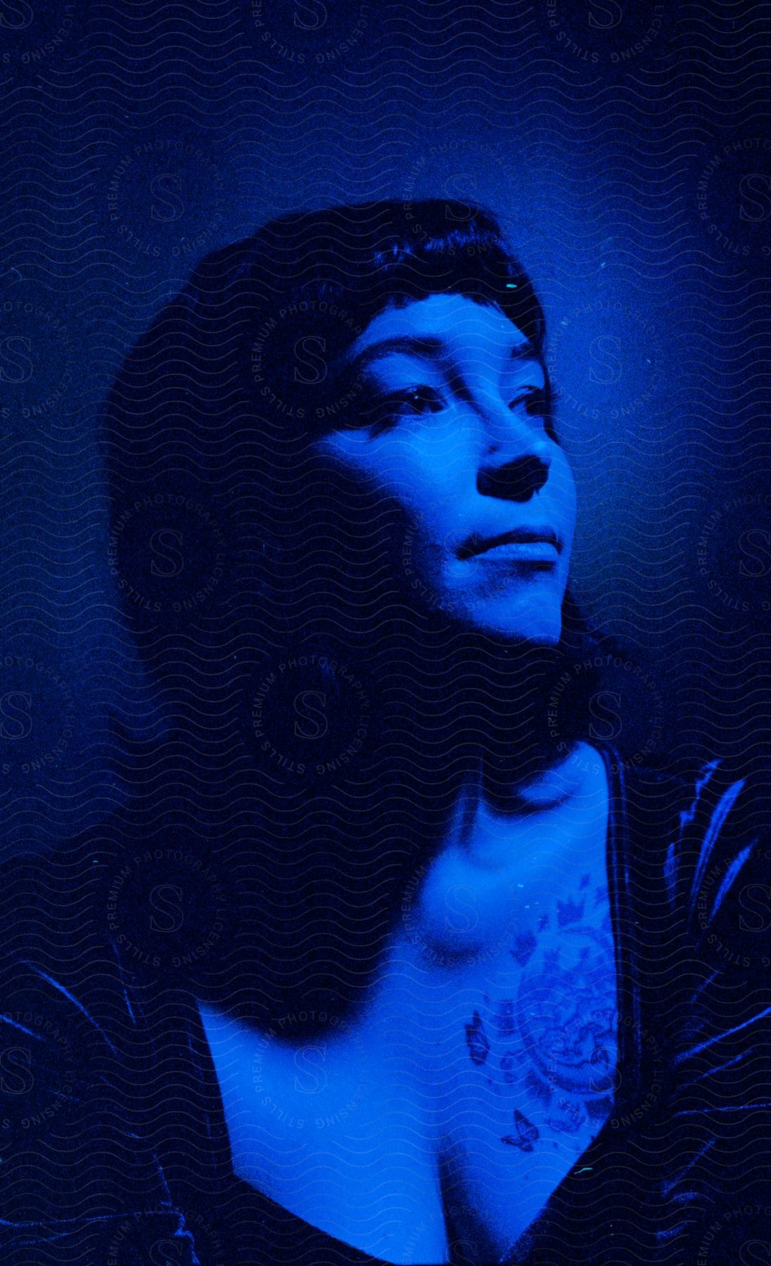 A woman stands gracefully in a captivating dark blue room