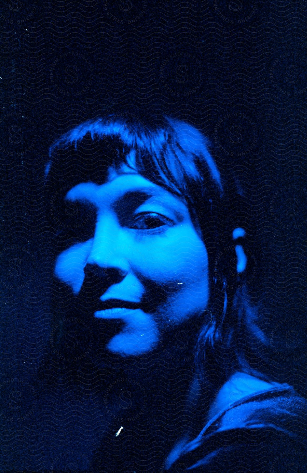 Close up of a young womans face looking at the camera under bright blue lights