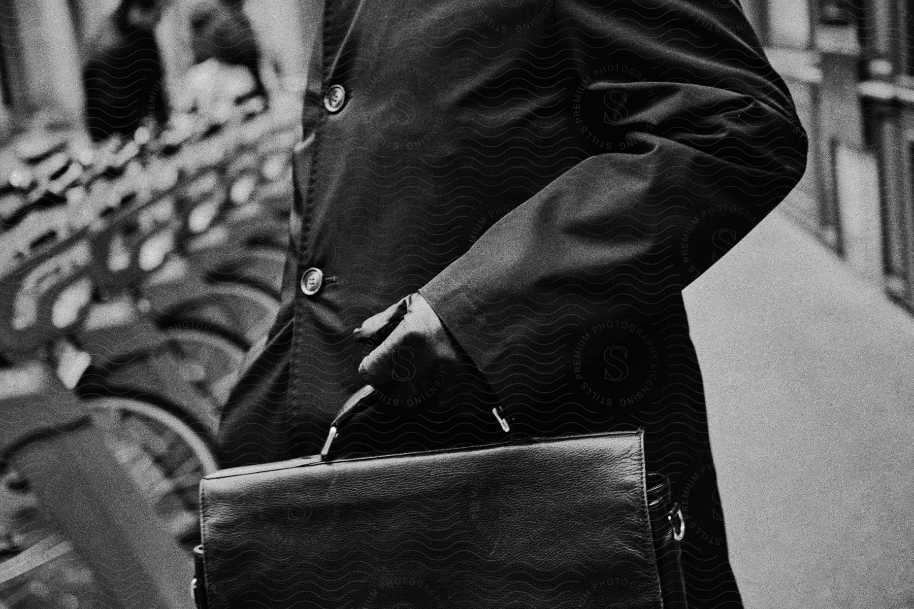 Man with black coat and gloves carries a briefcase next to bike racks