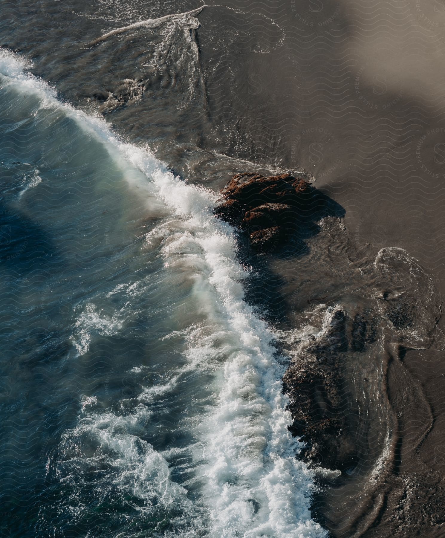 Aerial shot of ocean wave crashing against the sea