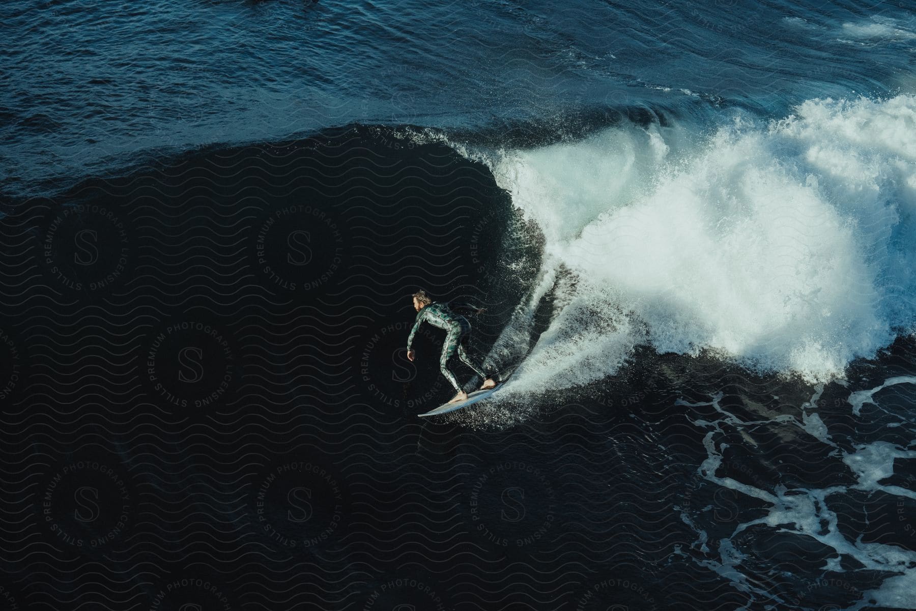 A man surfing on an ocean wave from an aerial perspective