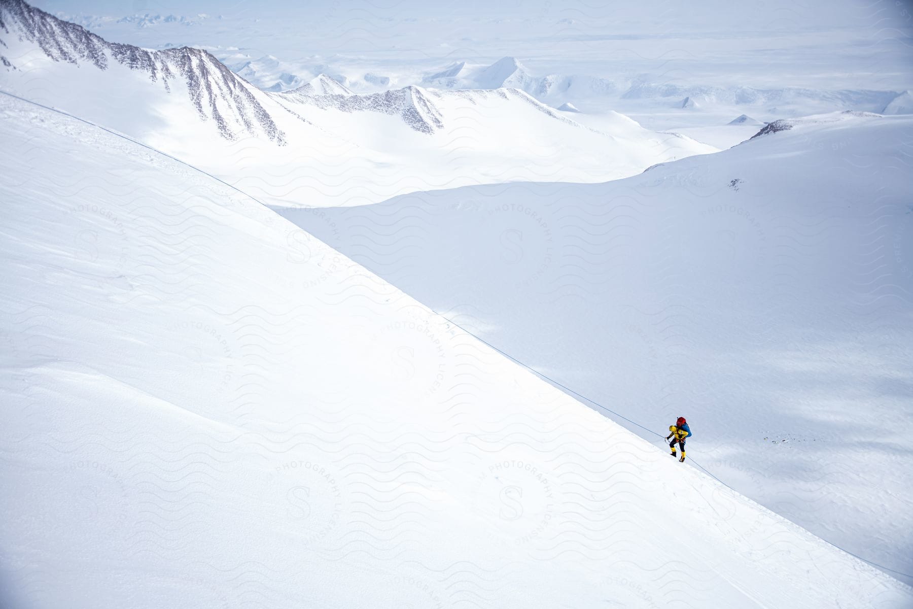 A person climbing snowy mountains in antarctica during the day