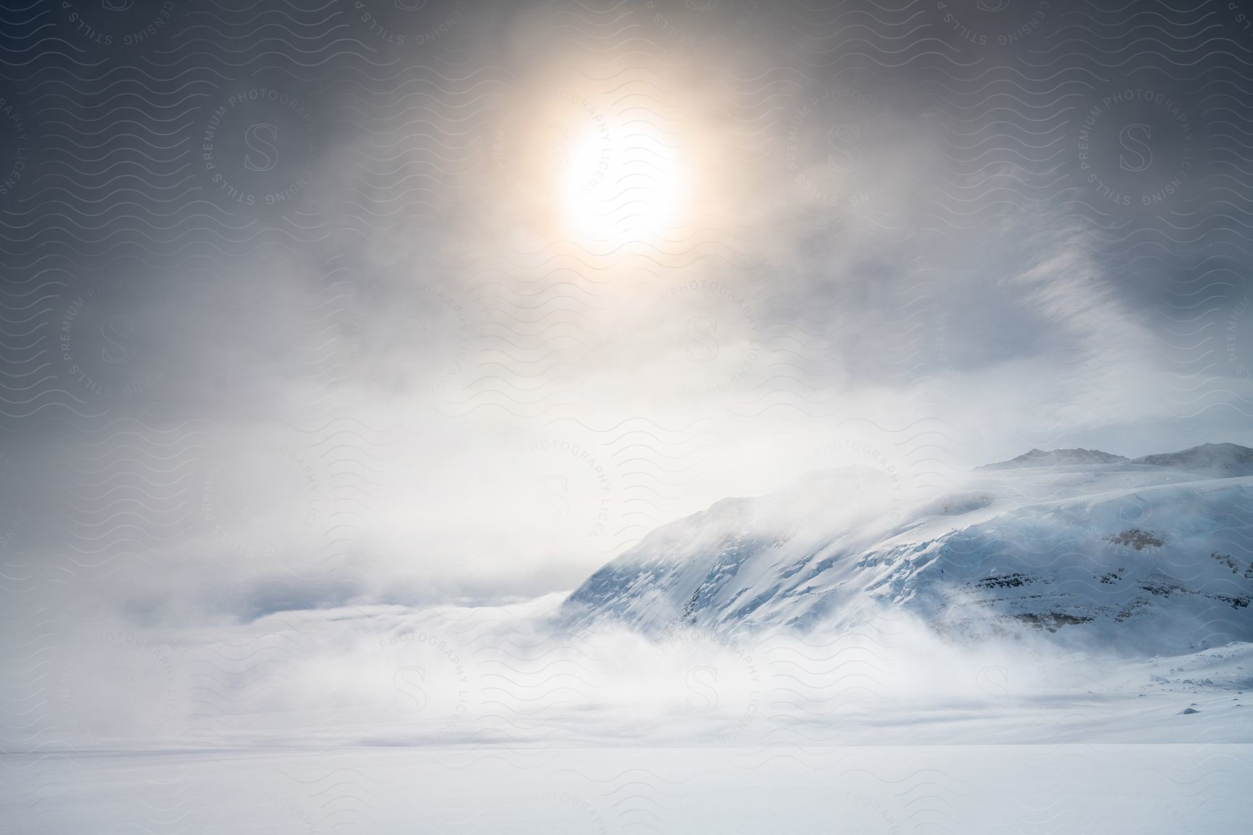 Snowcovered mountain landscape with clouds covering the sun in antarctica